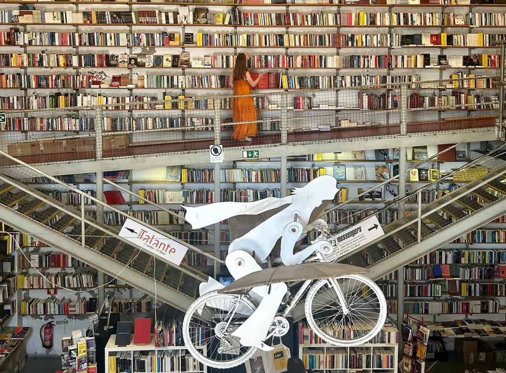 A large bookstore full of books with a bicycle art piece in the middle