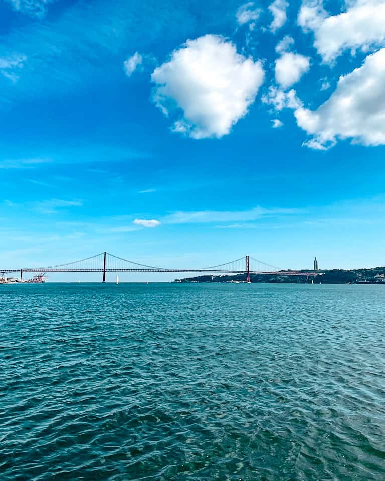 5 Days in Lisbon A view of the 25 De Abril Bridge above the Tagus River on a sunny day in Lisbon, Portugal