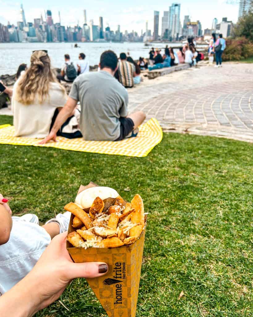 Smorgasburg in Williamsburg, New York on a summer day featuring people, views of New York City and french fries