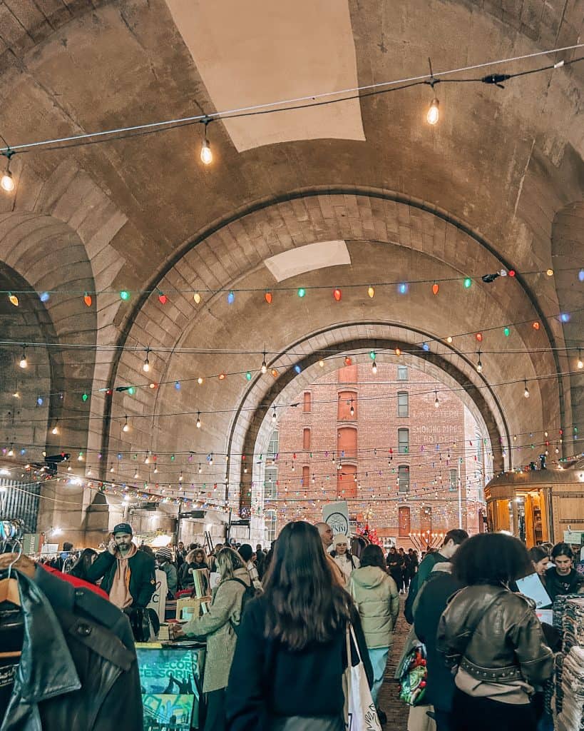 The Flea Market in Dumbo, New York with many people and holiday string lights