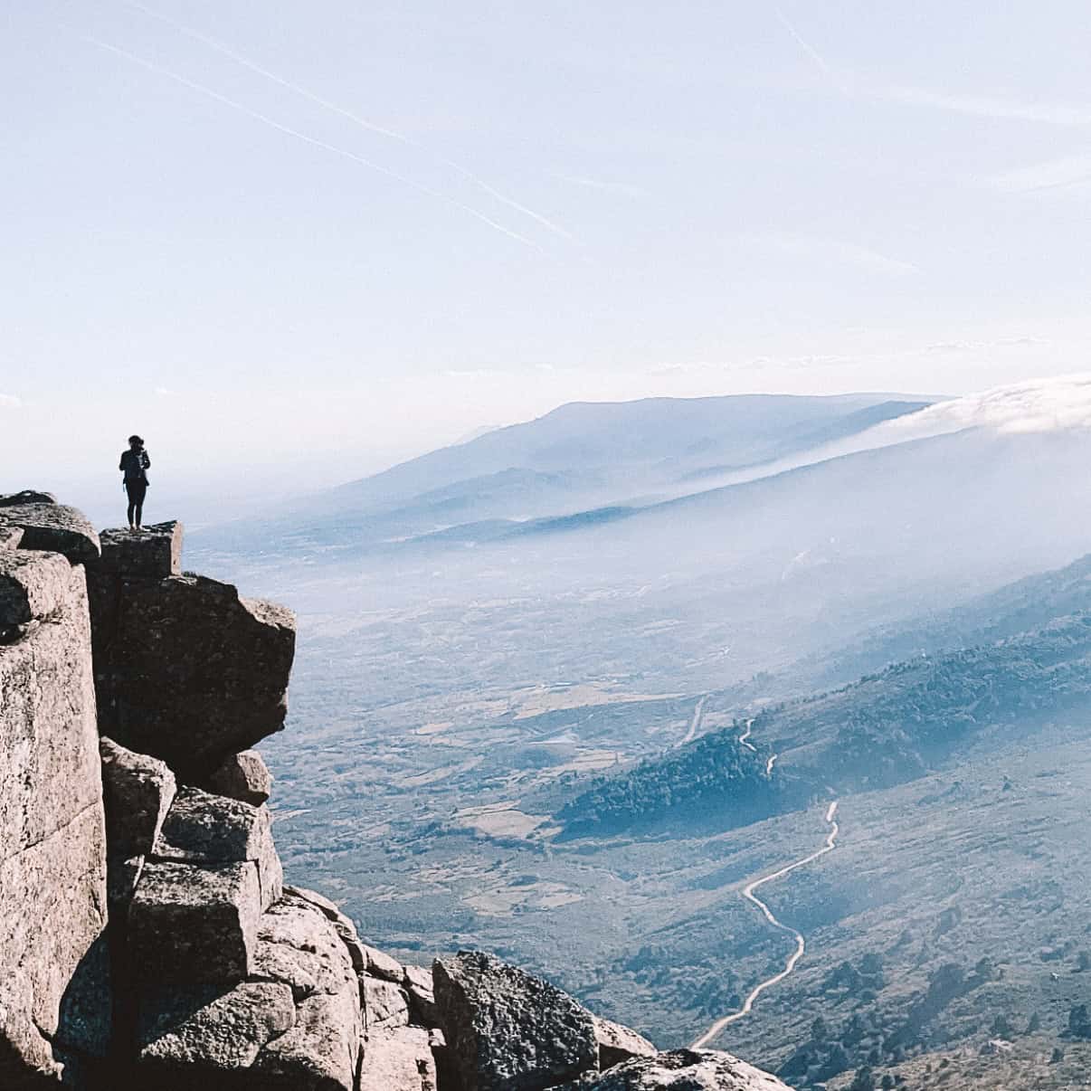 Living in Spain Woman standing on top of a cliff admiring the views on a hike in Cercedilla, Spain
