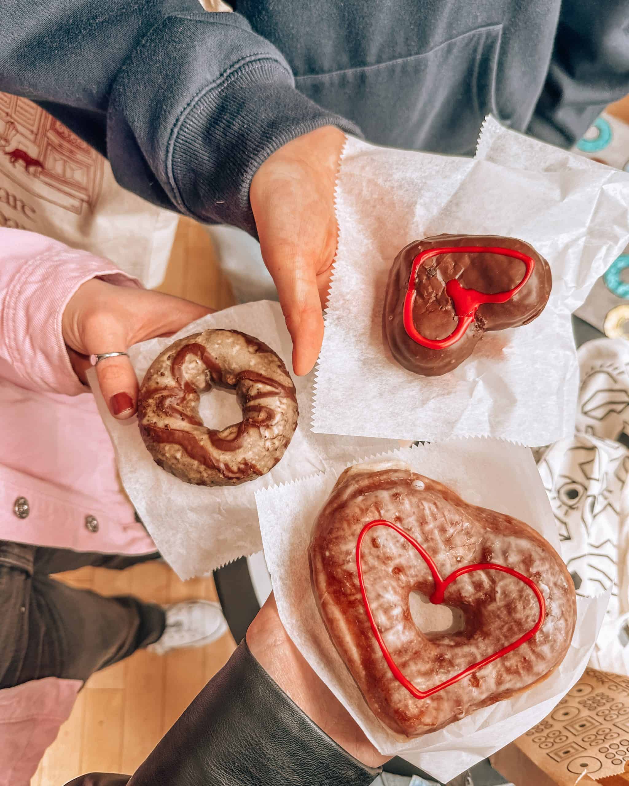 Three girls holding donuts from the Doughnut Plant in Brooklyn, New York