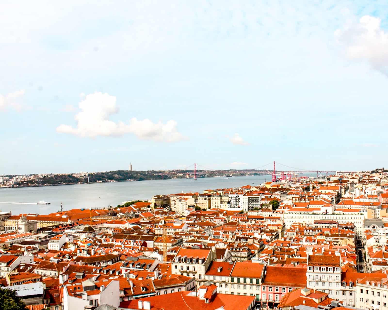 5 Days in Lisbon Expansive view of the Tagus River, 15 de Abril Bridge, and red rooftops in the city of Lisbon, Portugal