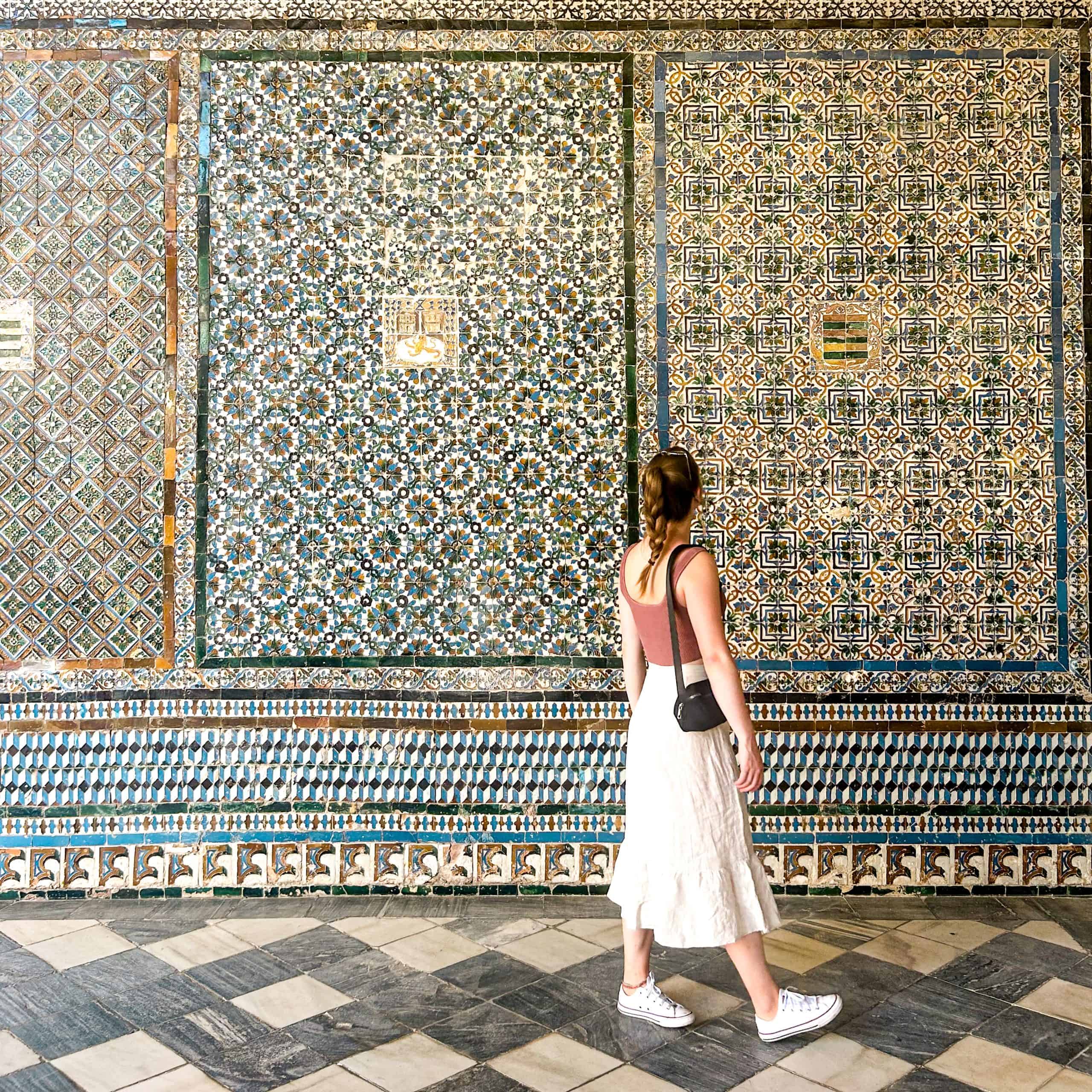 Living in Spain Woman admiring the beautiful, blue wall of tiles in Seville, Spain