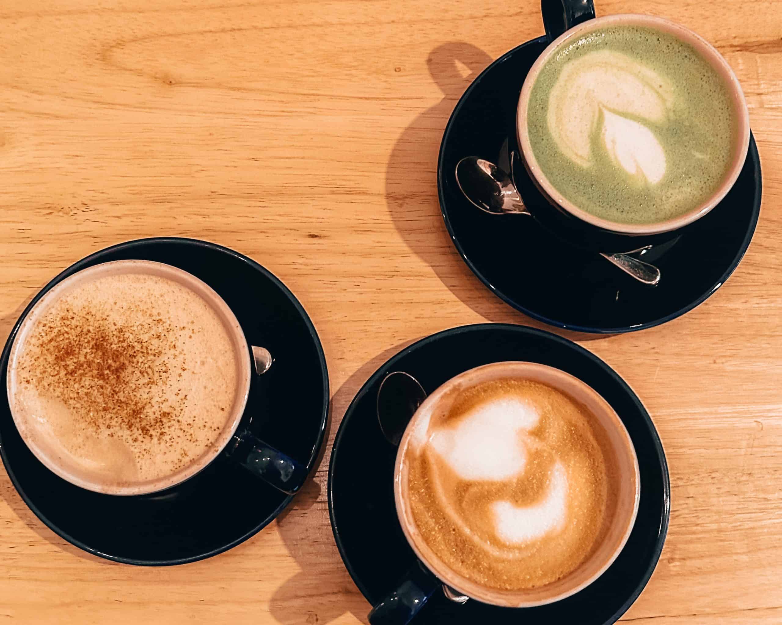 Three lattes on a wooden table at a coffee shop in Brooklyn, New York