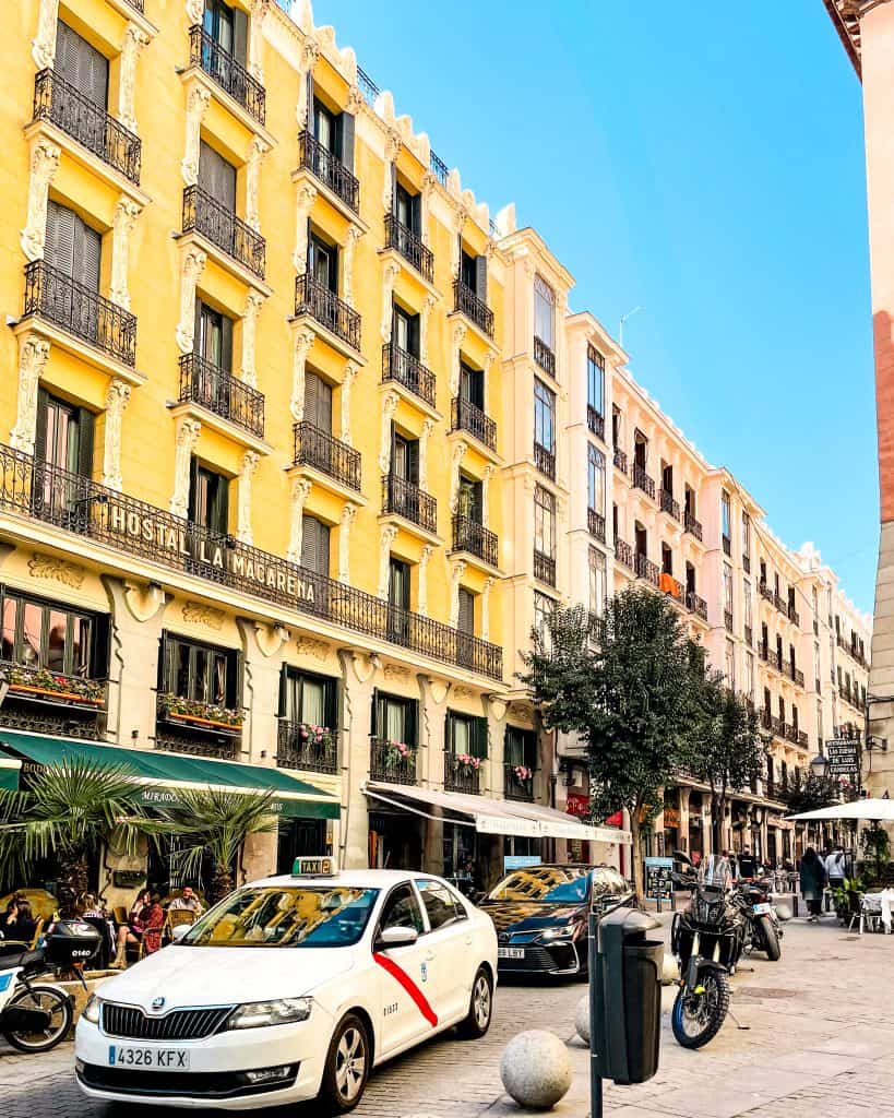 non-touristy things to do in Madrid Colorful buildings lining a road with cars in Madrid, Spain