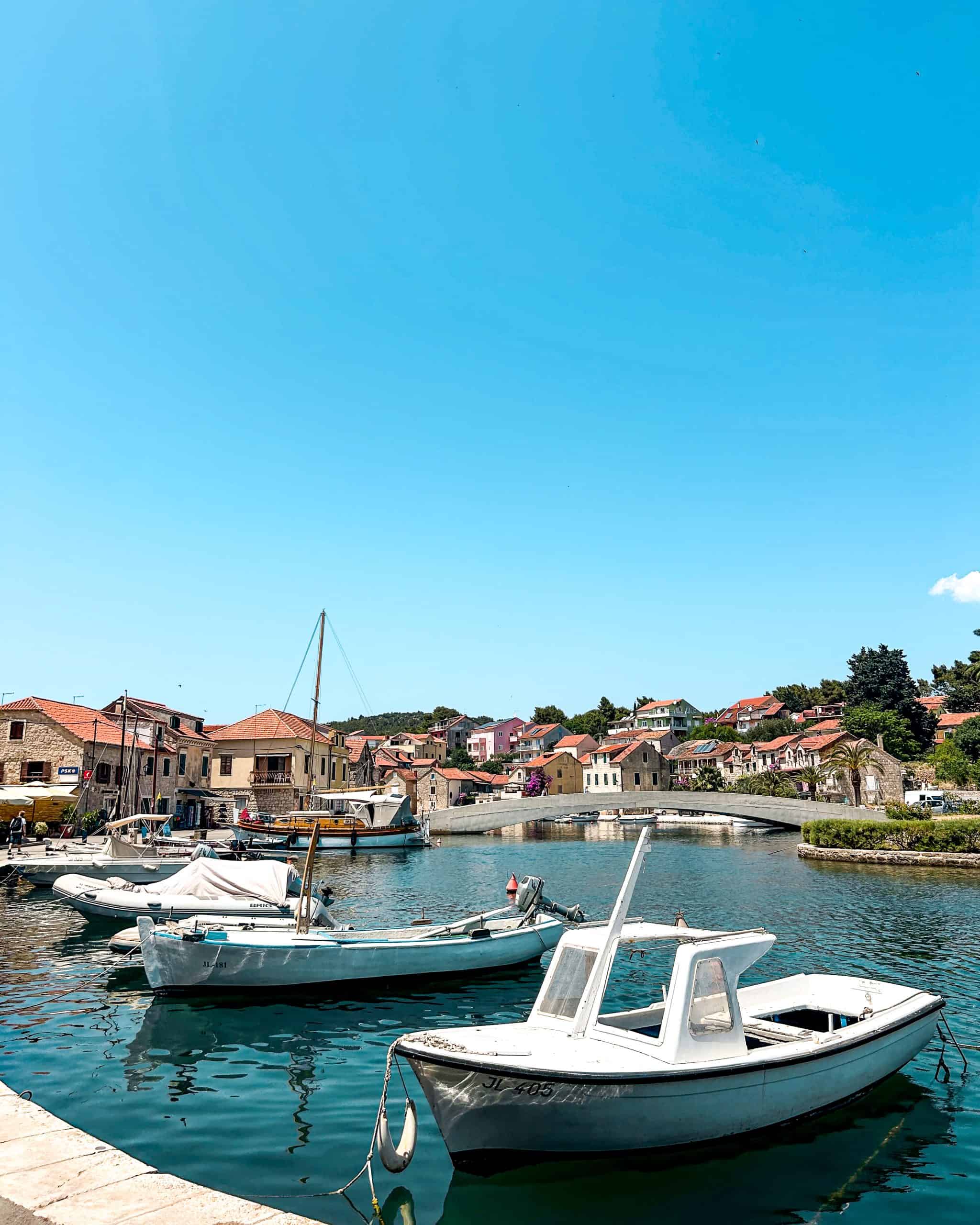 9 days in Croatia Boats in the harbor in Hvar, Croatia with a bridge and red-roofed buildings in the background