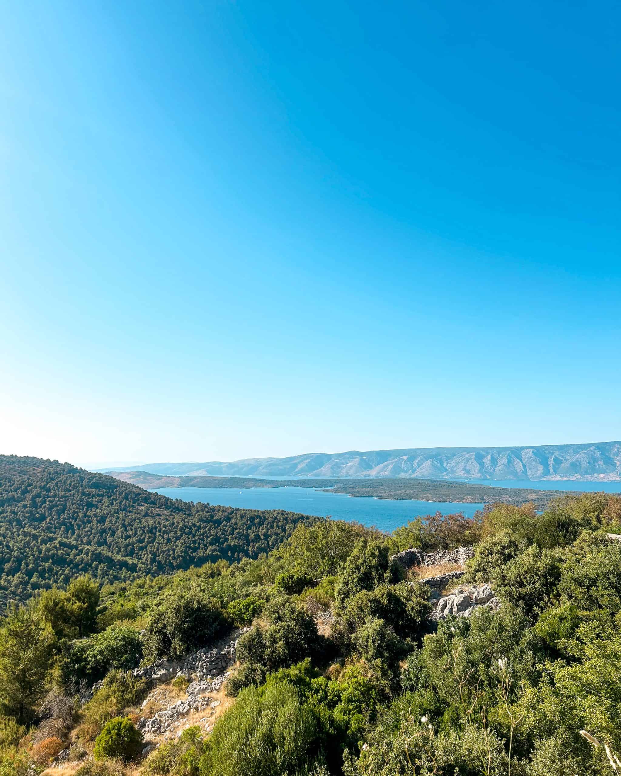 Is Croatia worth visiting? A stunning expanse of rolling hills with trees with a view of the sea below in Croatia