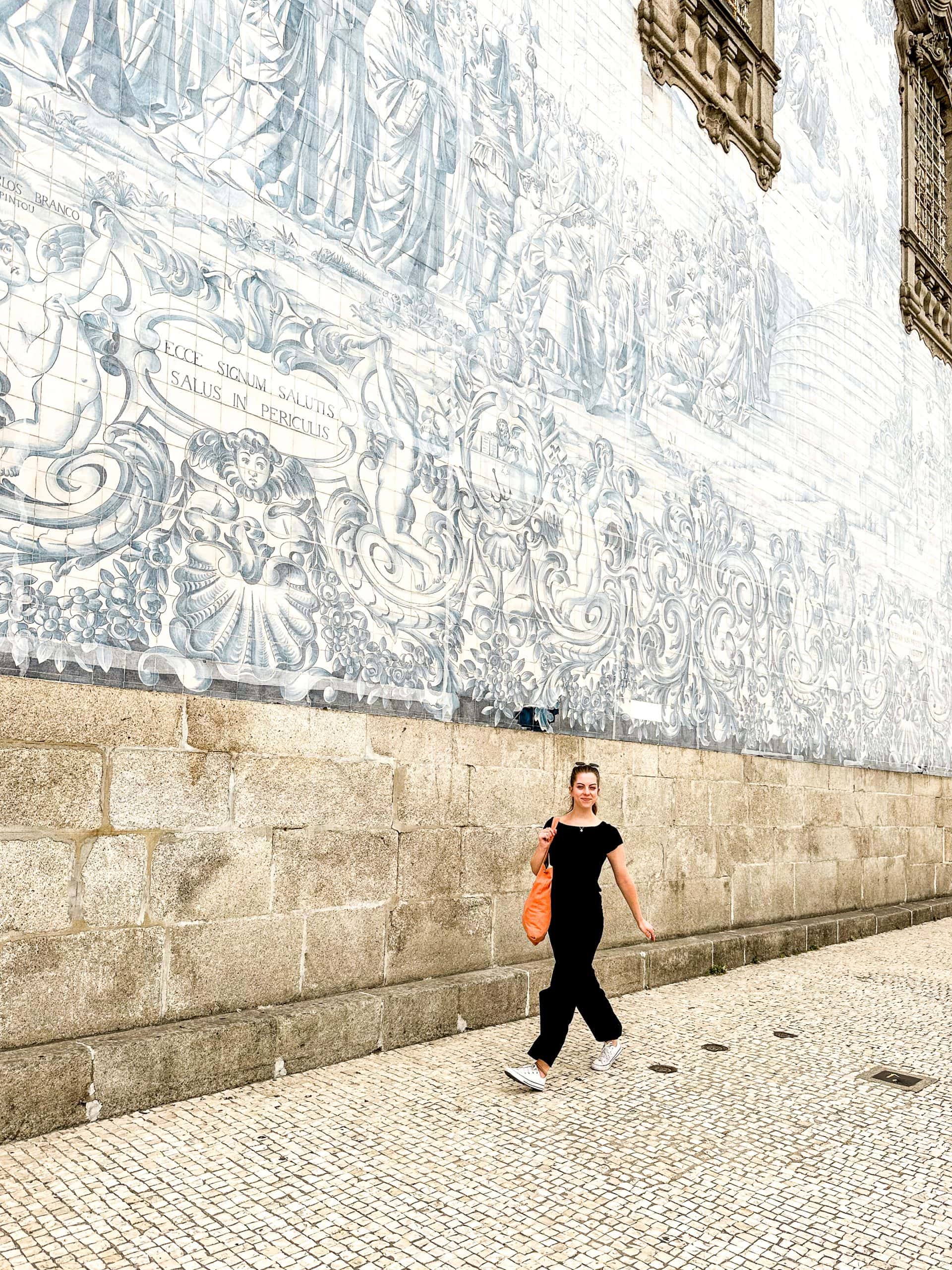 Woman walking in front of the blue and white tiled side of the Igreja do Carmo church in Porto, Portugal