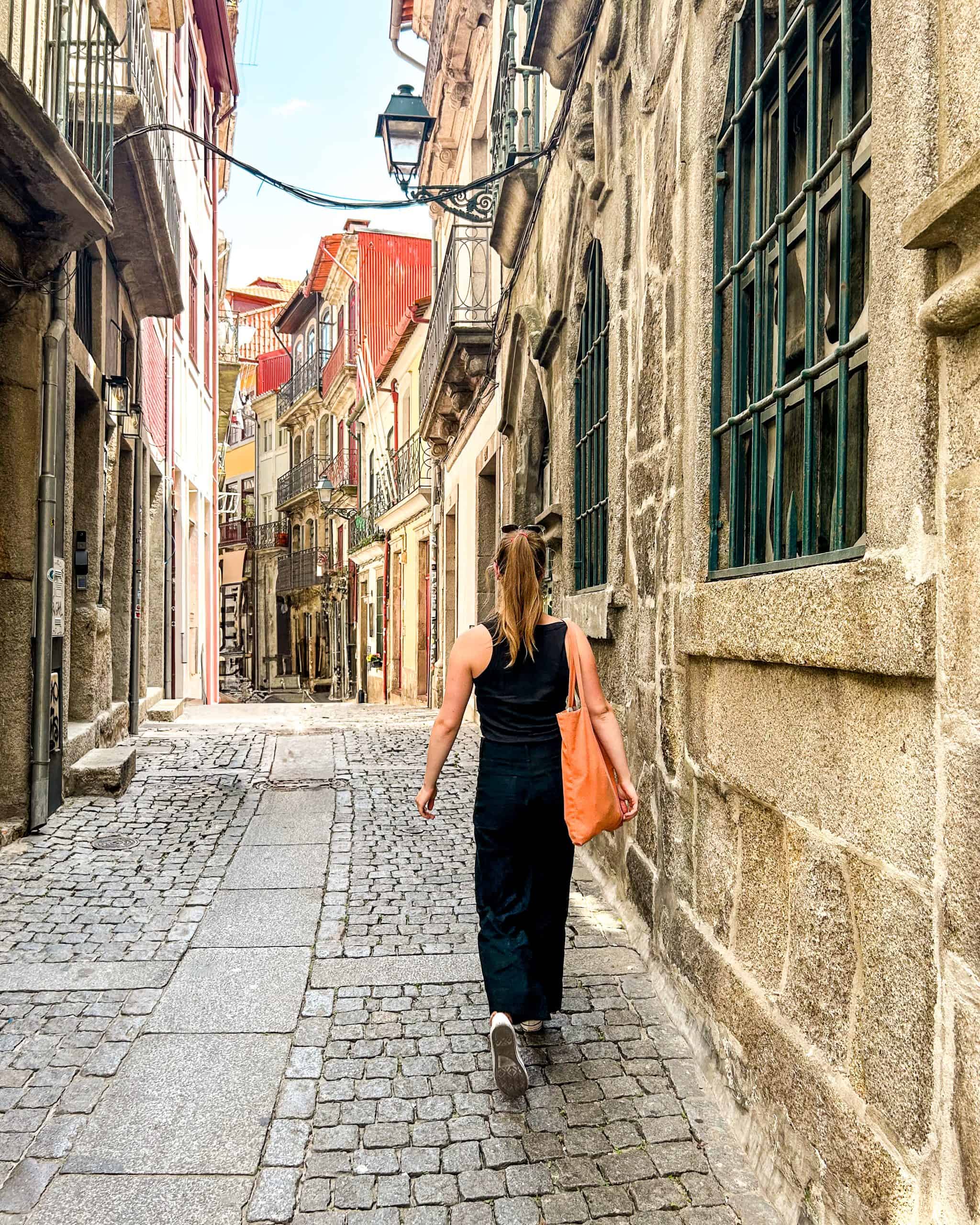 Woman walking down an empty narrow street in Porto, Portugal