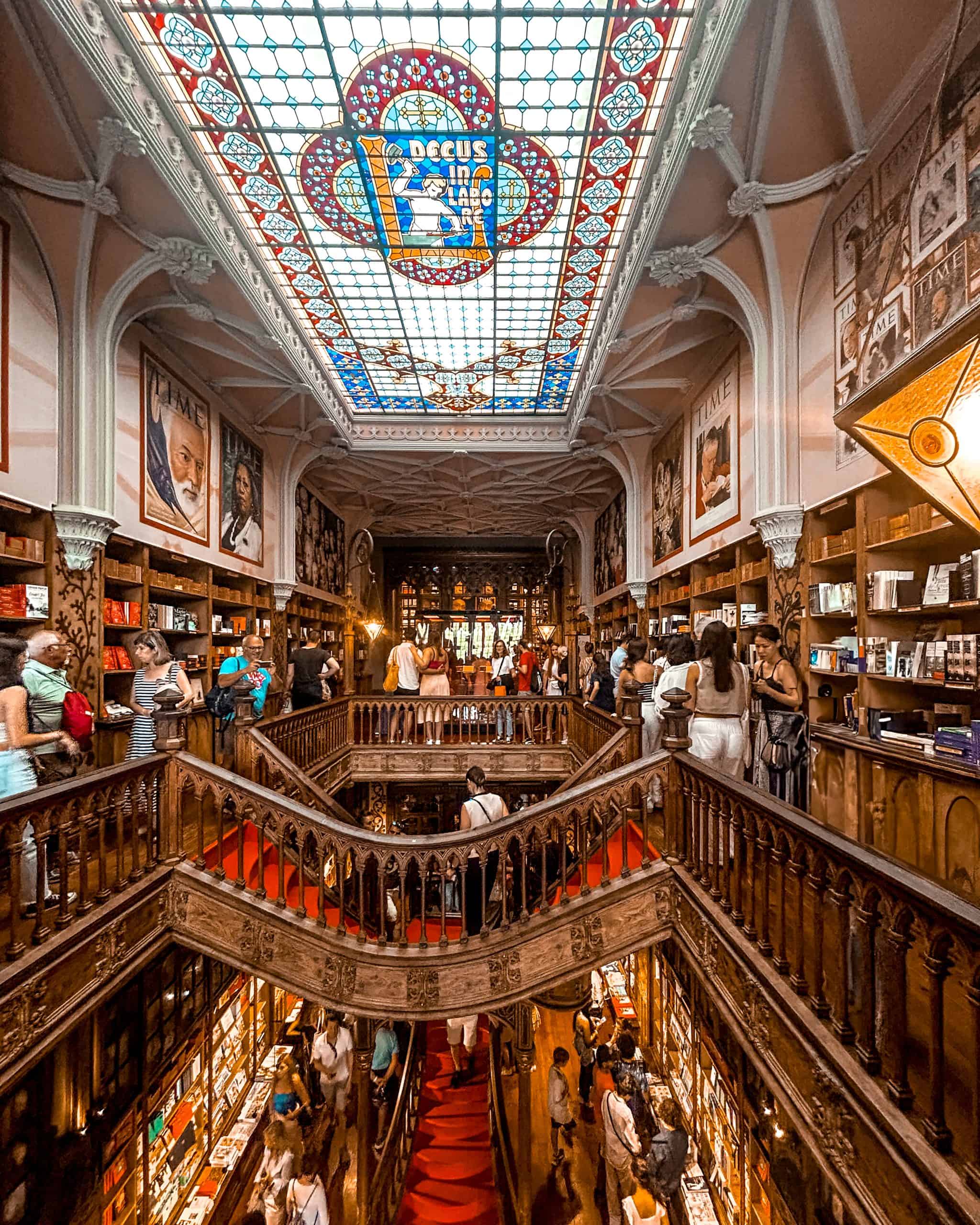 Interior of the famous bookstore, Livraria Lello, featuring the stain-glass ceiling and wooden staircases in Porto, Portugal