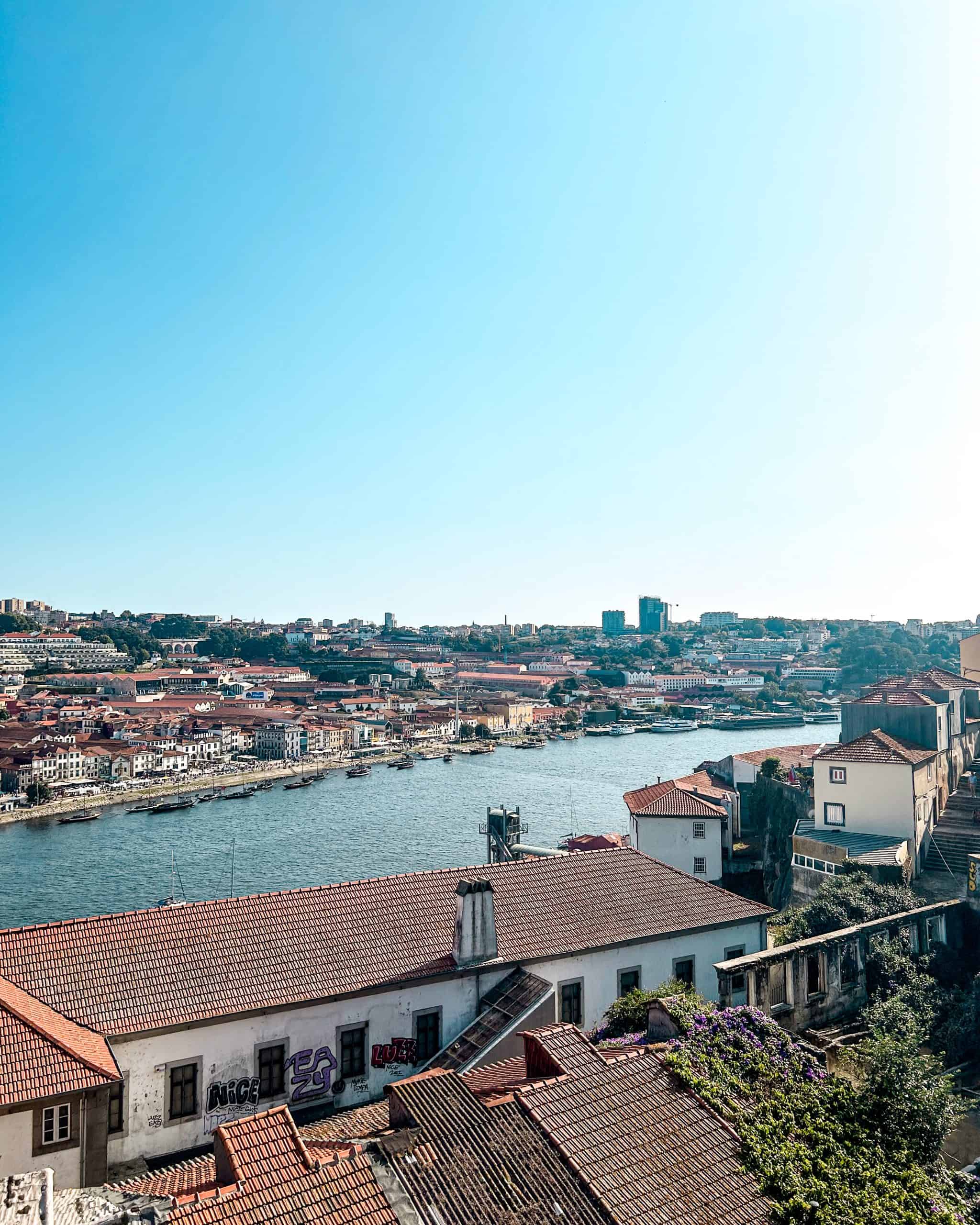 Douro River in Porto, Portugal with surrounding buildings with red roofs on a sunny day