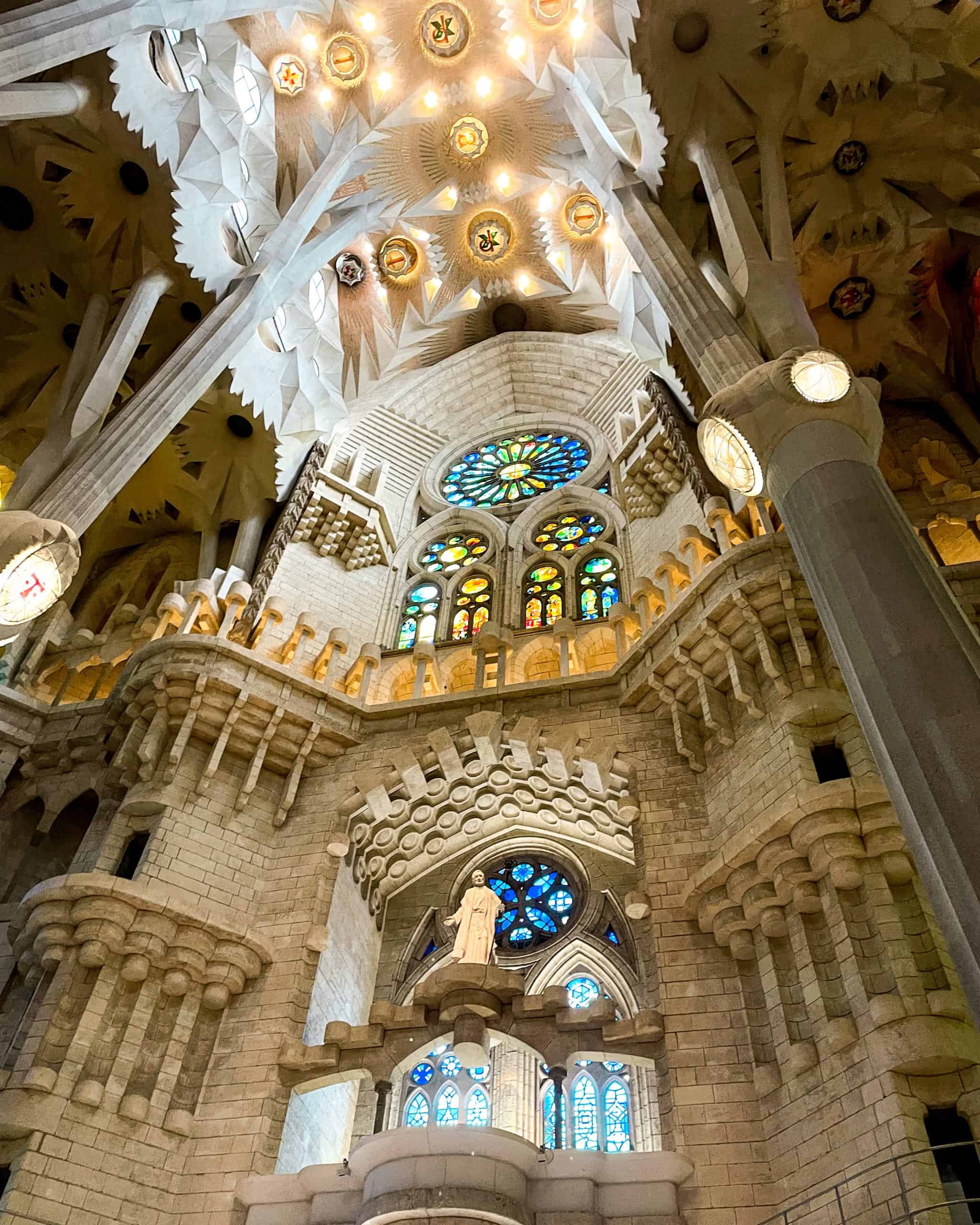 the intricate, detailed interior featuring statues, large pillars, and stain-glass windows in the Sagrada Família in Barcelona, Spain