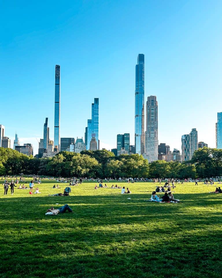 People having a picnic in Sheep Meadow on a late afternoon at Central Park with skyscrapers in the background