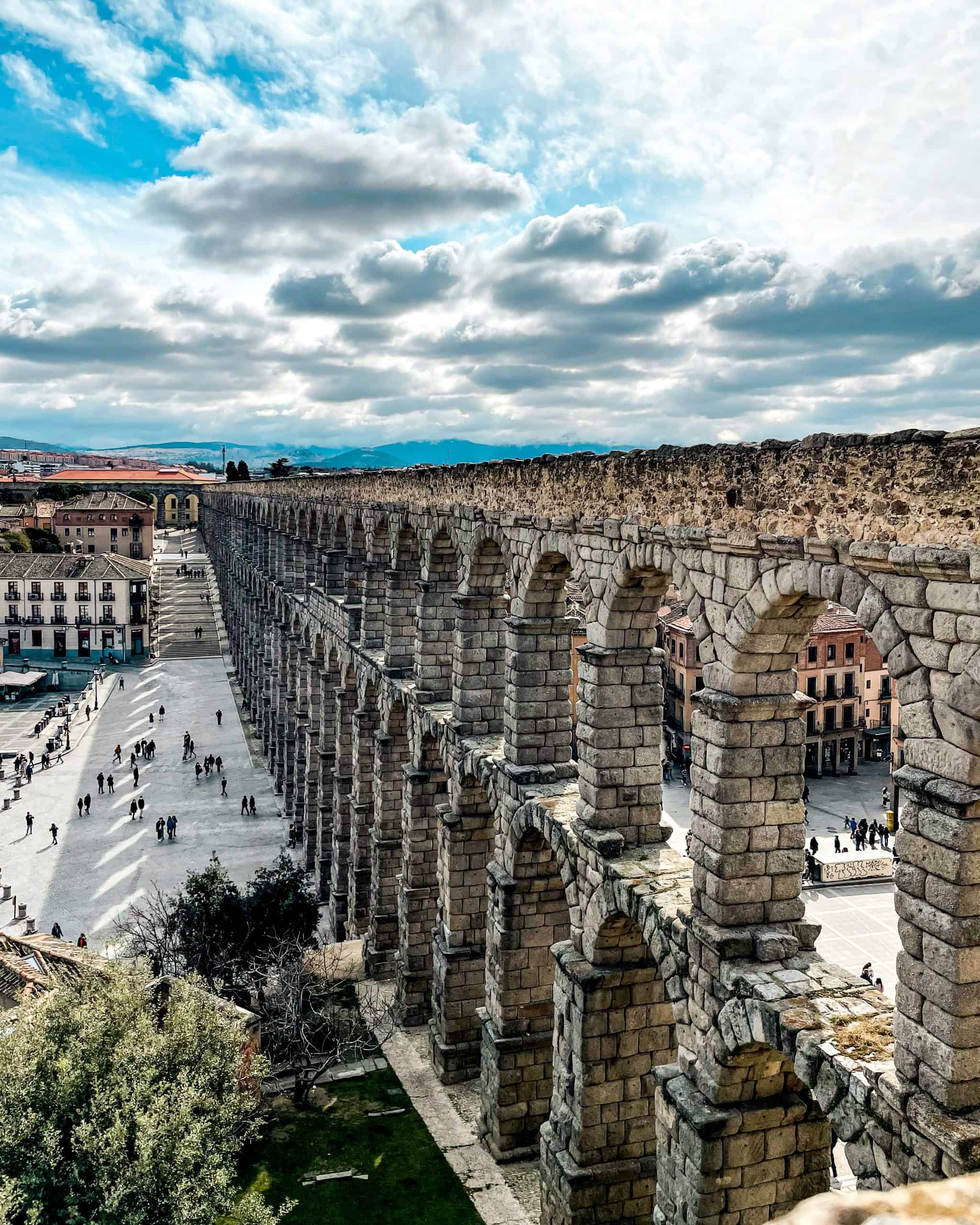 The famous aqueduct featuring large stone arches forming a wall in Segovia, Spain