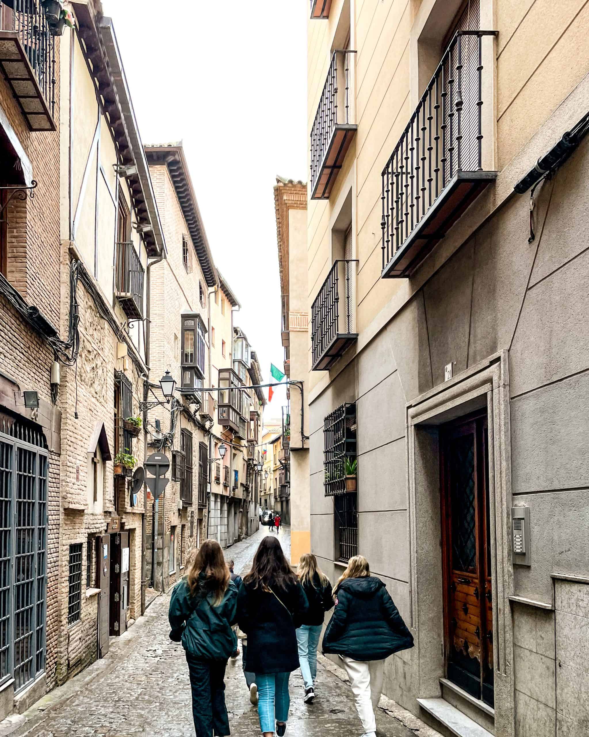 a group of women strolling through the narrow cobblestone streets in Toledo, Spain