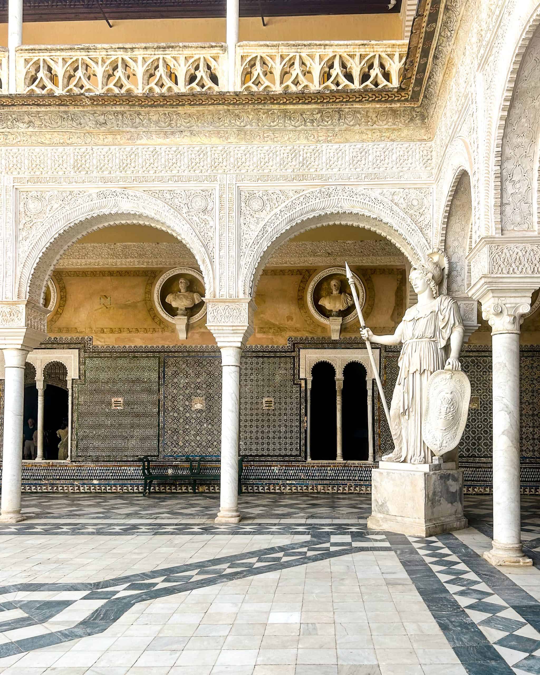 Statue and intricate, detailed architecture and tiled floors and walls at Casa de Pilatos in Seville, Spain