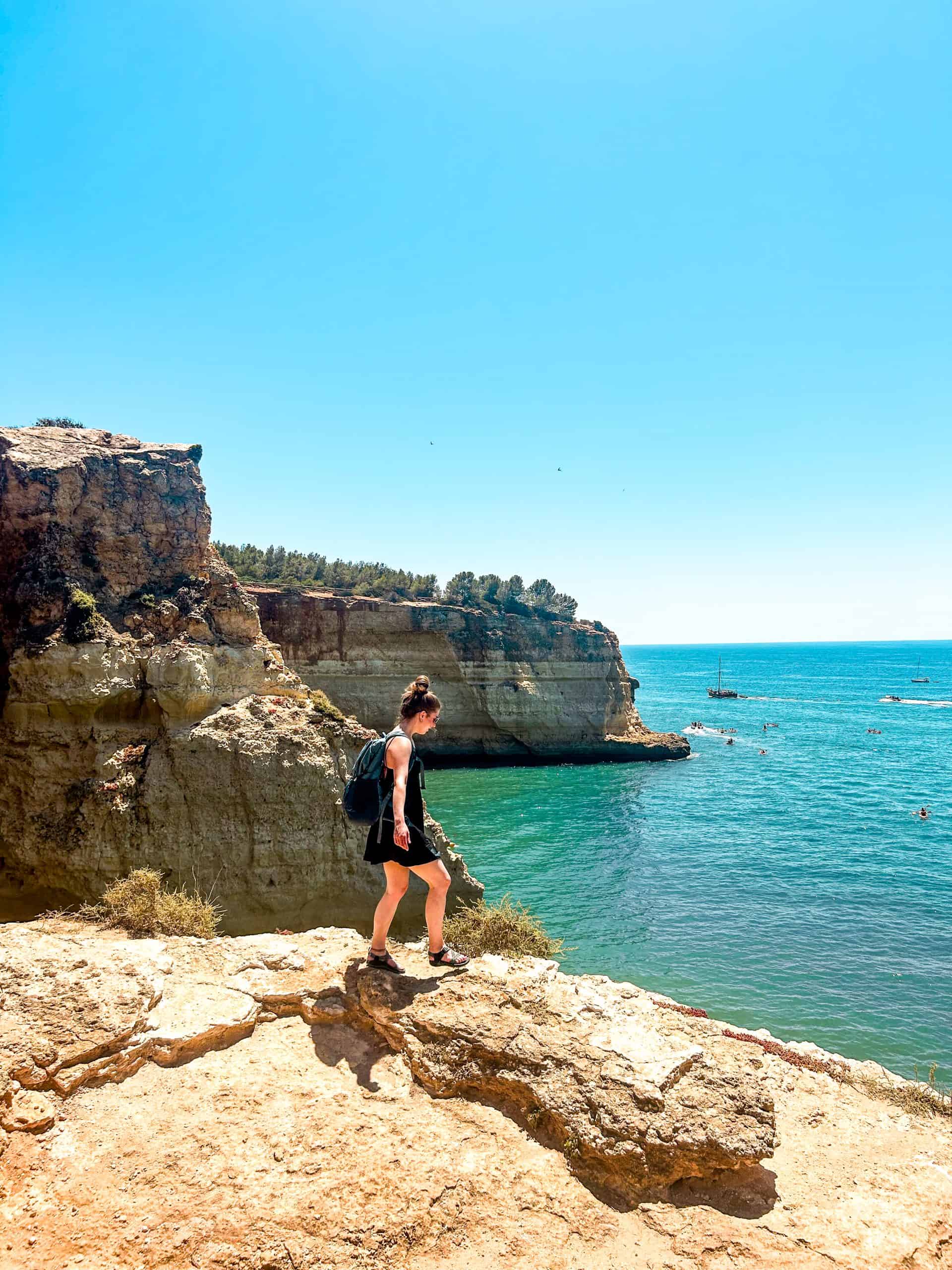 woman standing on a cliff's edge with cliffs and the ocean in the background in the Algarve Coast, Portugal
