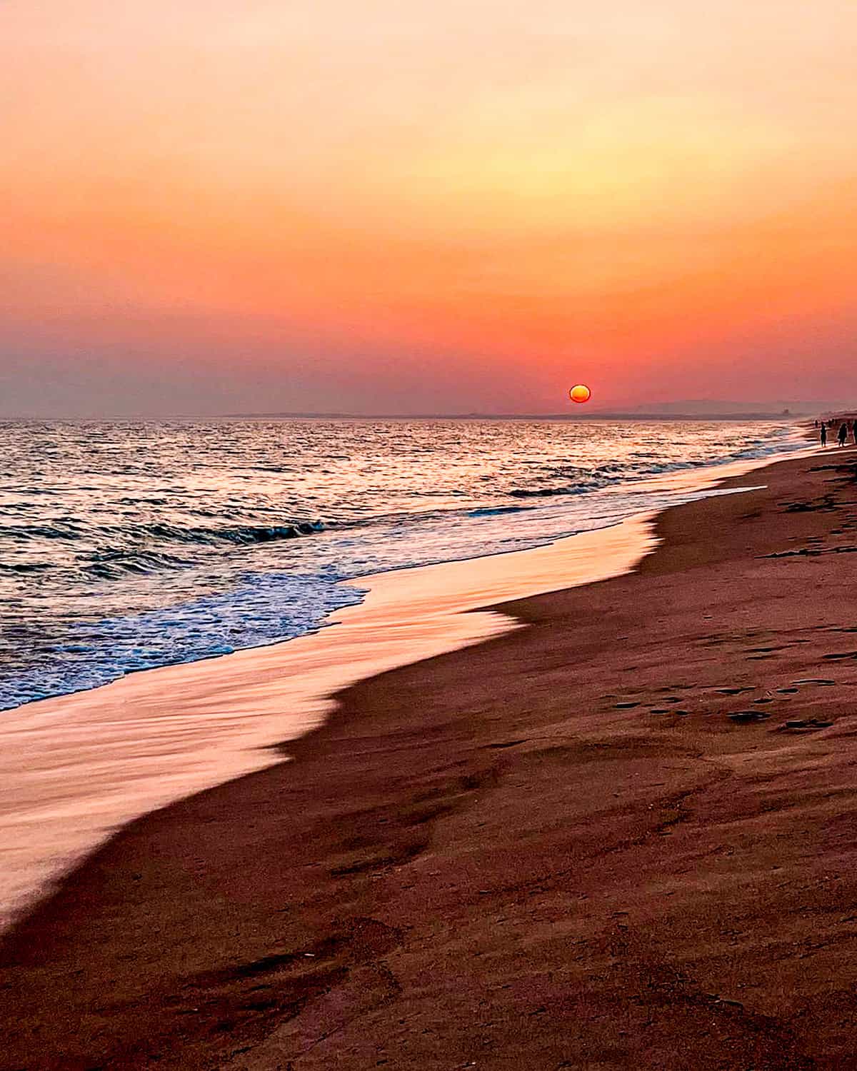 sunset with pink and orange clouds at the beach in Faro, Portugal