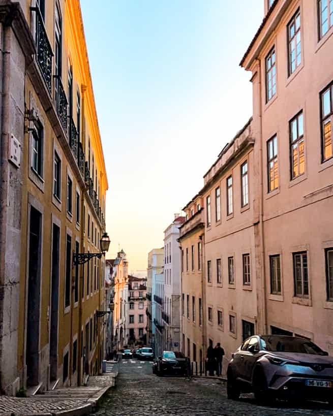 Where to stay in Lisbon neighborhood street with colorful buildings in Lisbon, Portugal at dusk