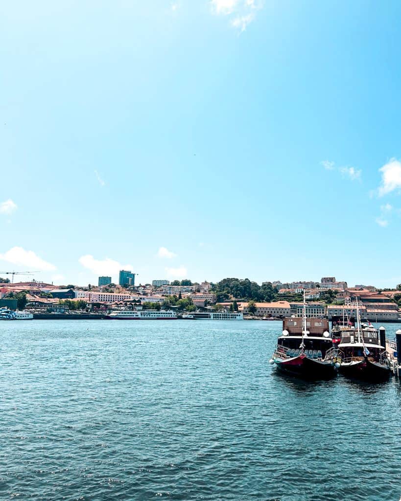 Where to Stay in Porto Douro River with two boats in the harbor with a view of buildings and the blue sky in the background