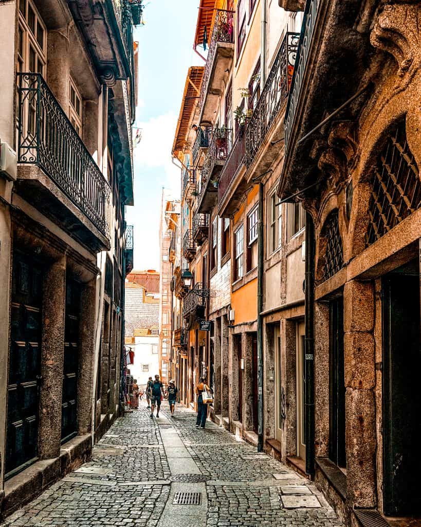 Where to Stay in Porto narrow alleyway with cobblestones and historic buildings in Baixa, Porto, Portugal