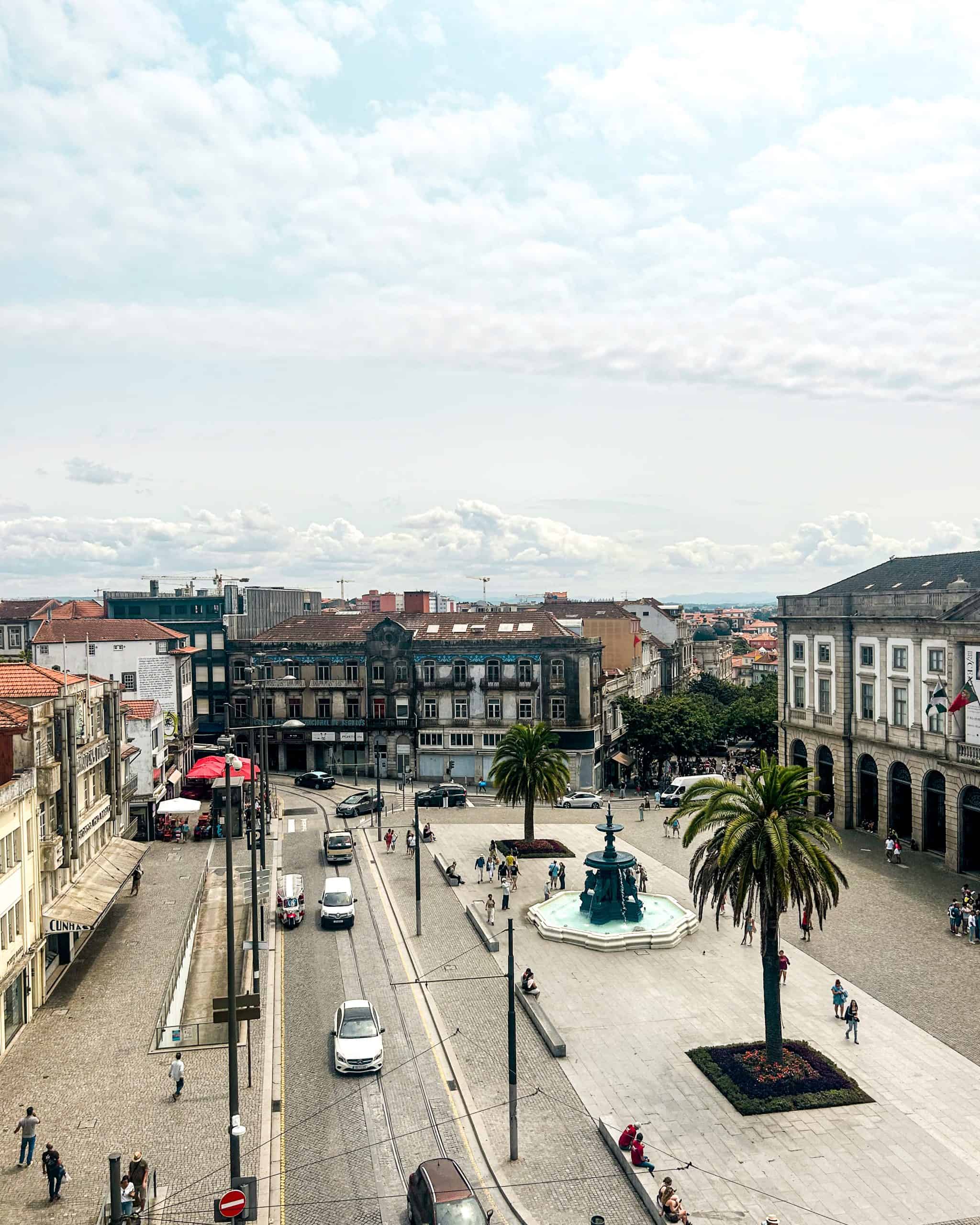 Where to Stay in Porto Quiet square in Vitória, Porto, Portugal with cars, cobblestone streets, historic buildings, and palm trees