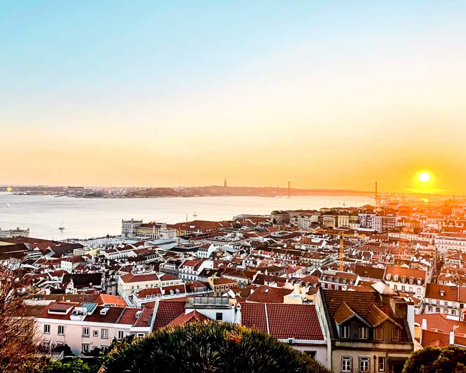 Sunset viewpoint over Lisbon’s terracotta rooftops and the Tagus River in Portugal.