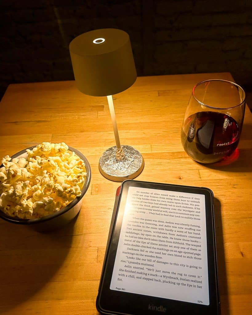 kindle, glass of wine, and popcorn at a local wine bar in NYC at night