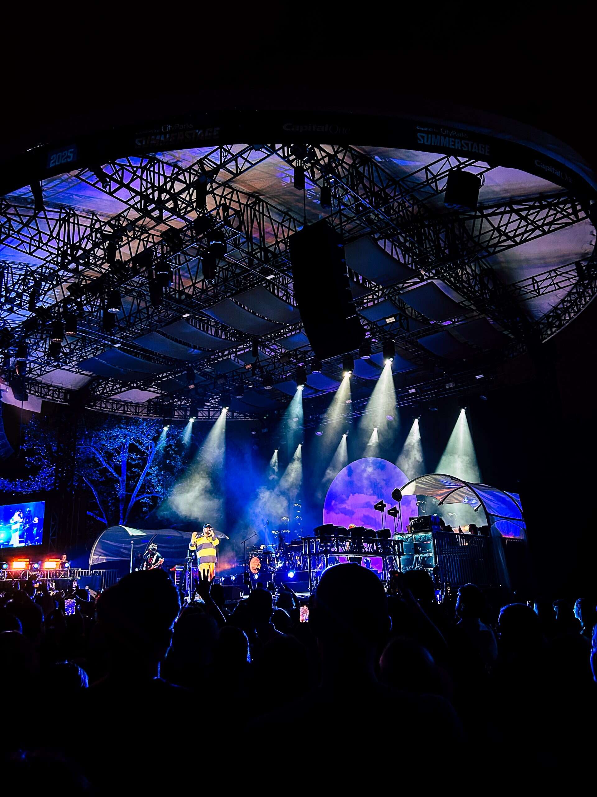 lit up stage with a musician at the live music venue in Central Park in NYC at night