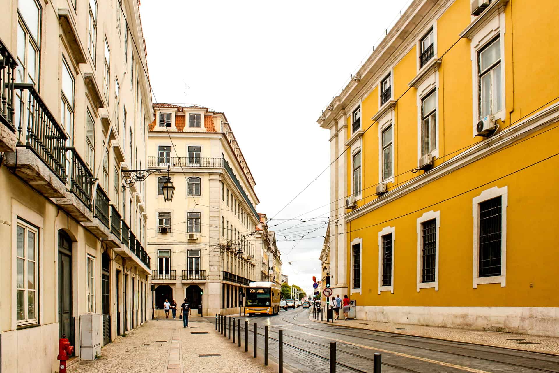 Street view of yellow and white buildings and a passing tram in downtown Lisbon, Portugal.