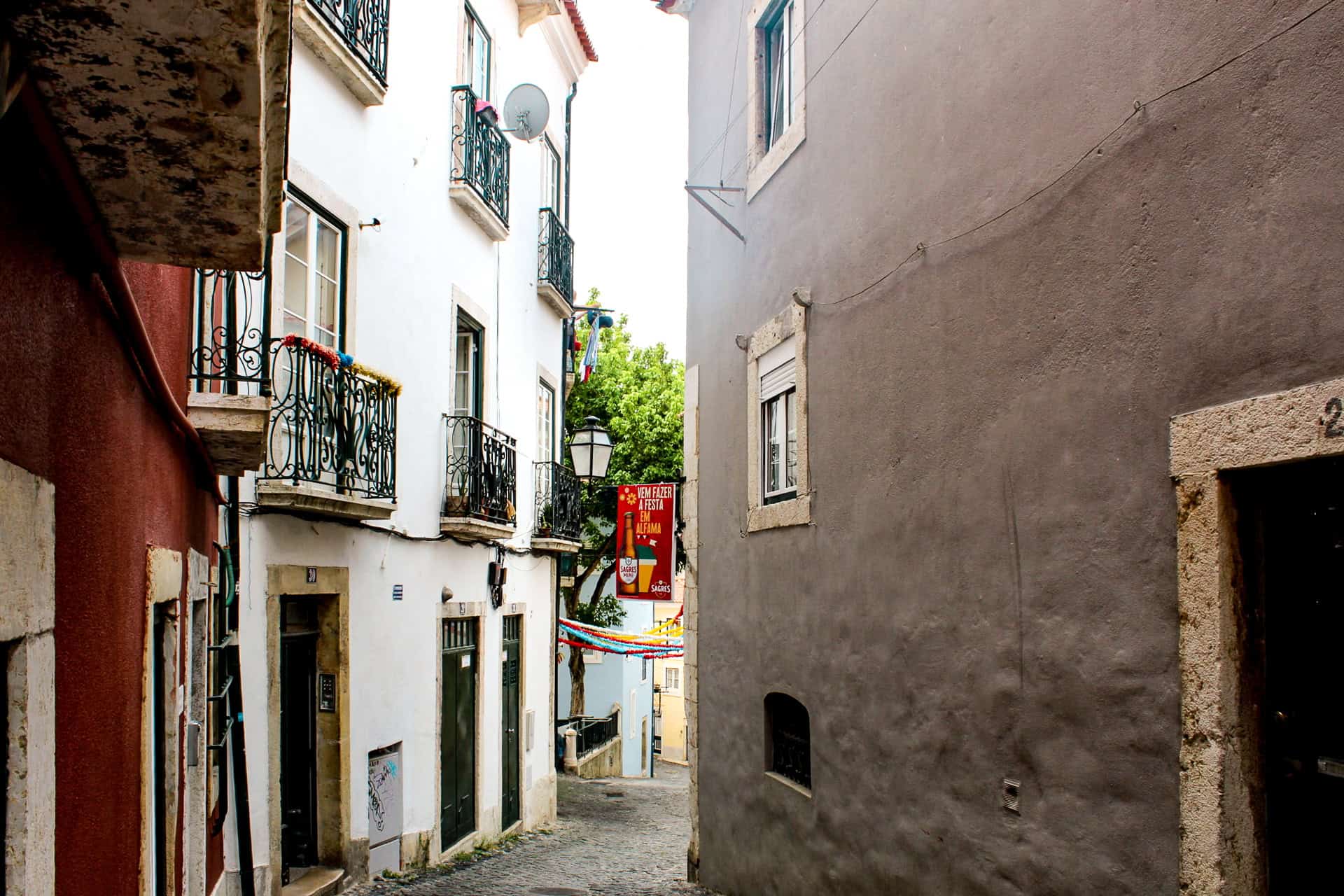 Colorful cobblestone alleyway in Lisbon, Portugal, decorated with banners and traditional balconies