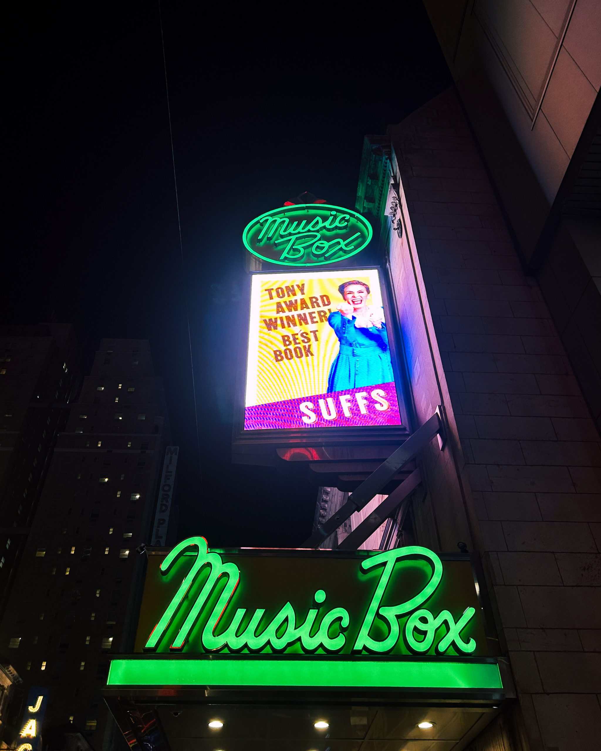 a broadway show sign and lights in NYC at night