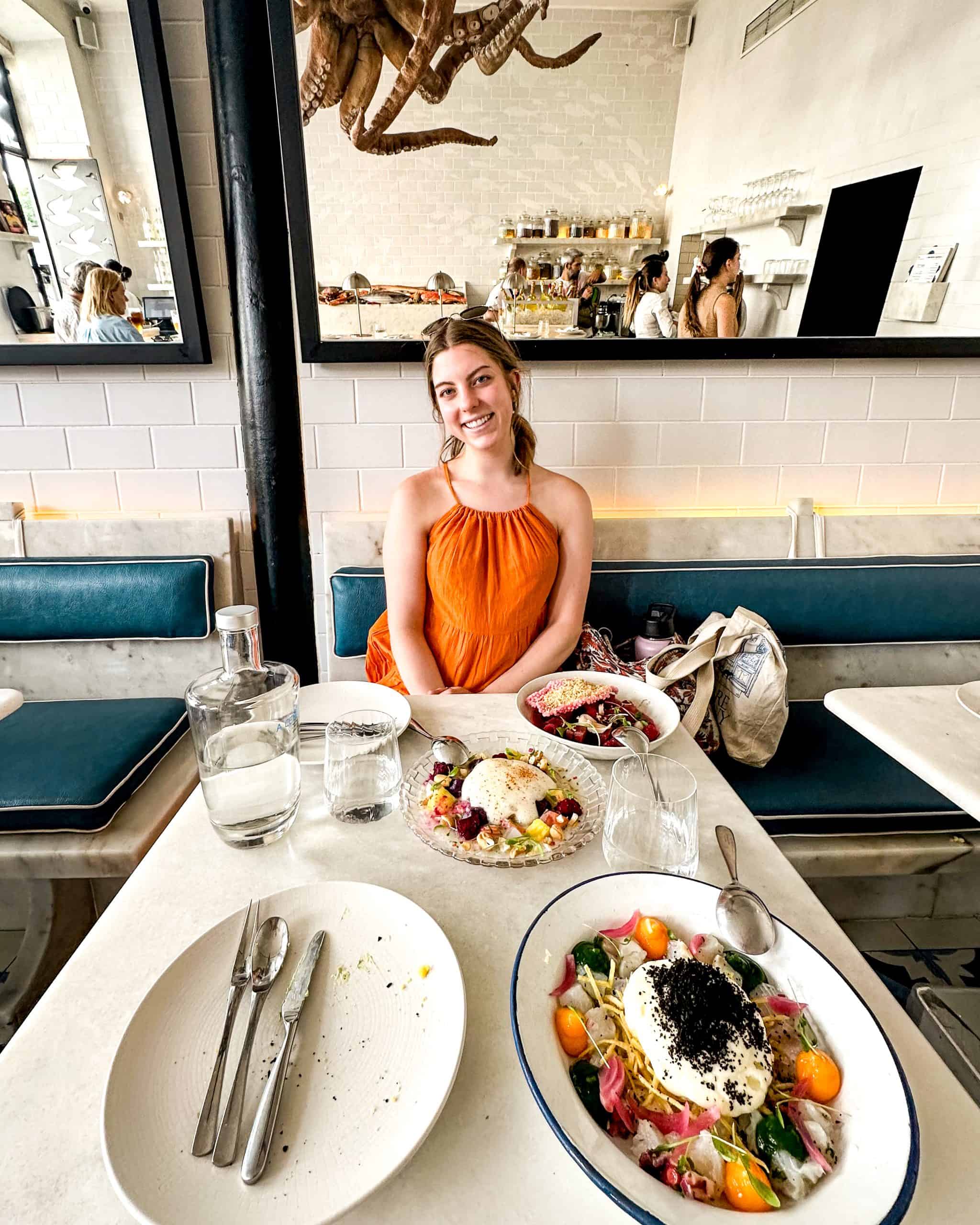 Woman enjoying brunch at a bright, modern café in Lisbon, Portugal, with vibrant dishes on the table