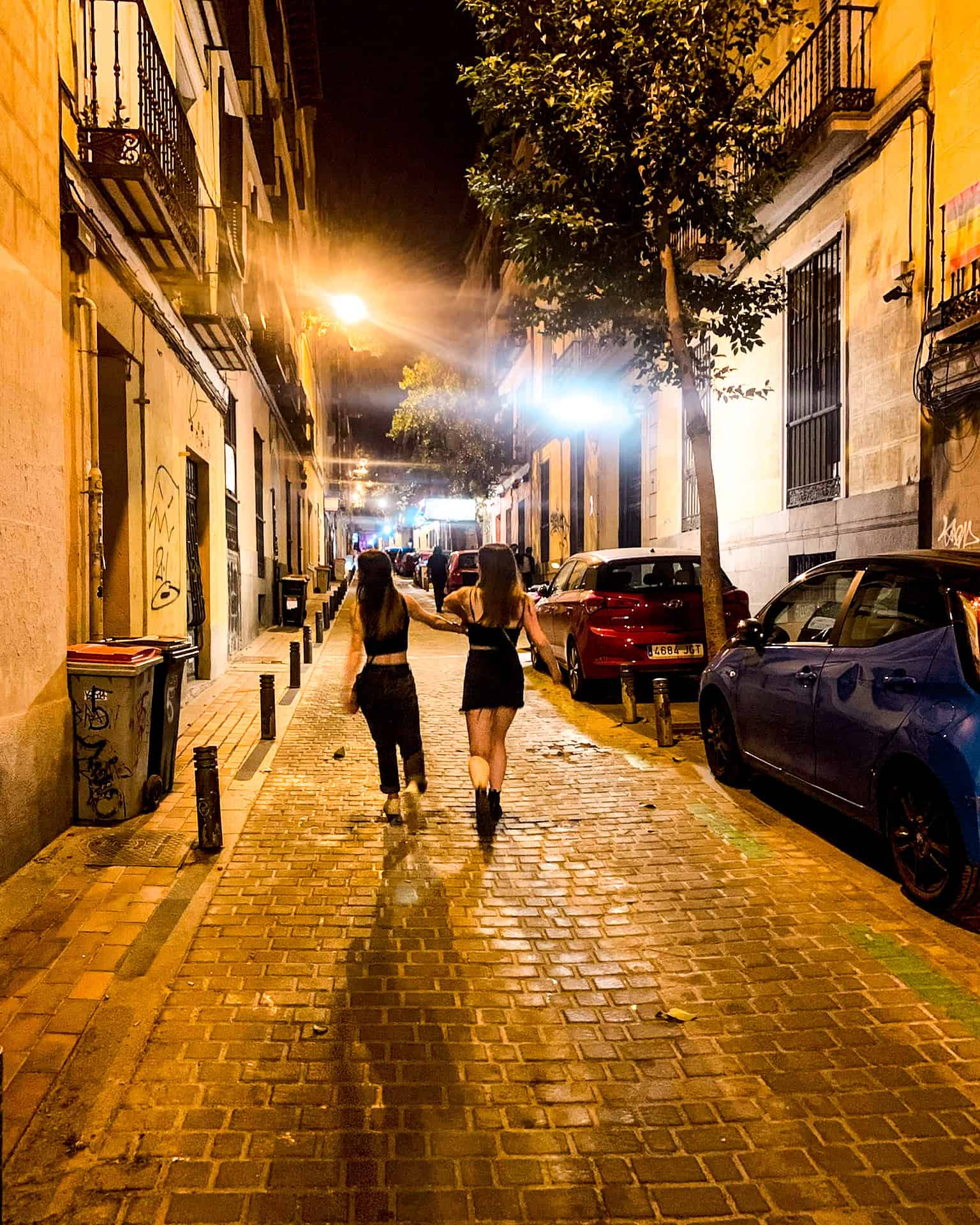 two women walking down the street at night in Madrid, Spain