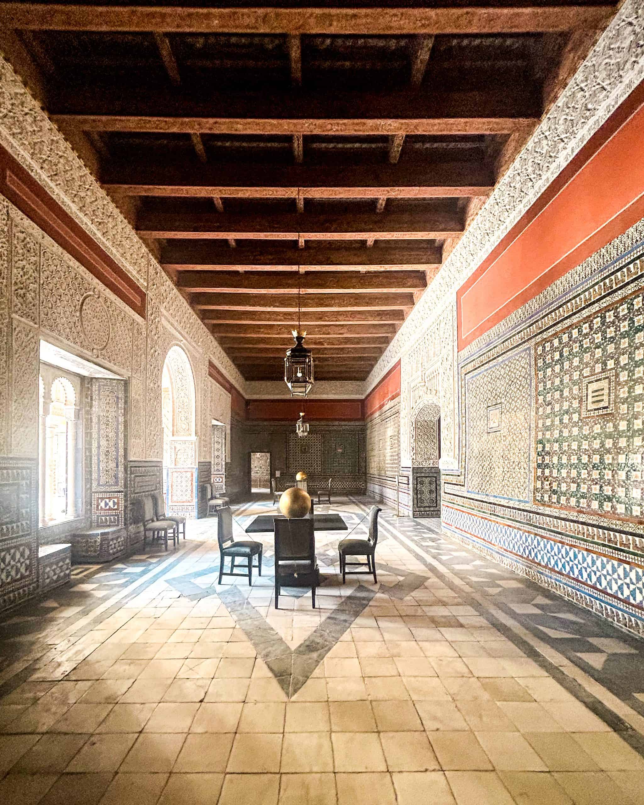 Moorish-style interior room inside Casa de Pilatos in Seville, Spain, showcasing intricate tilework, arched doorways, and classic Andalusian architecture.