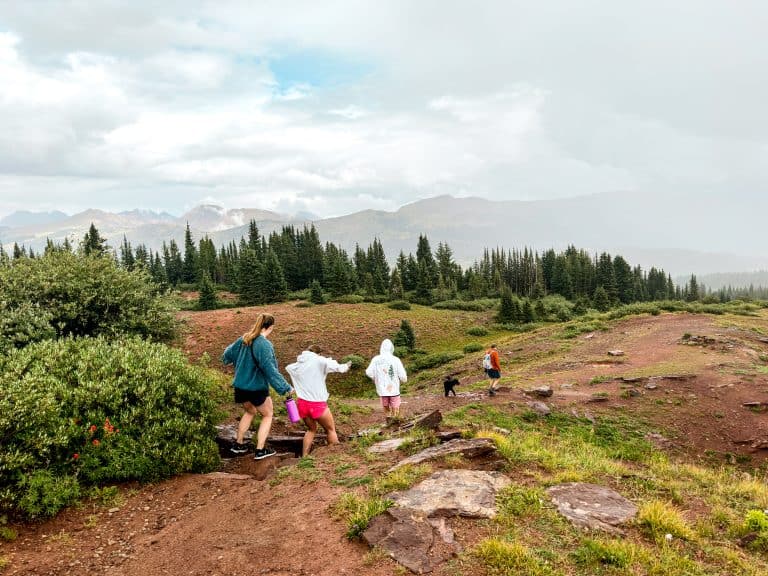 Group of friends hiking in the mountains near Vail, Colorado, with alpine scenery, rocky trails, and evergreen forests