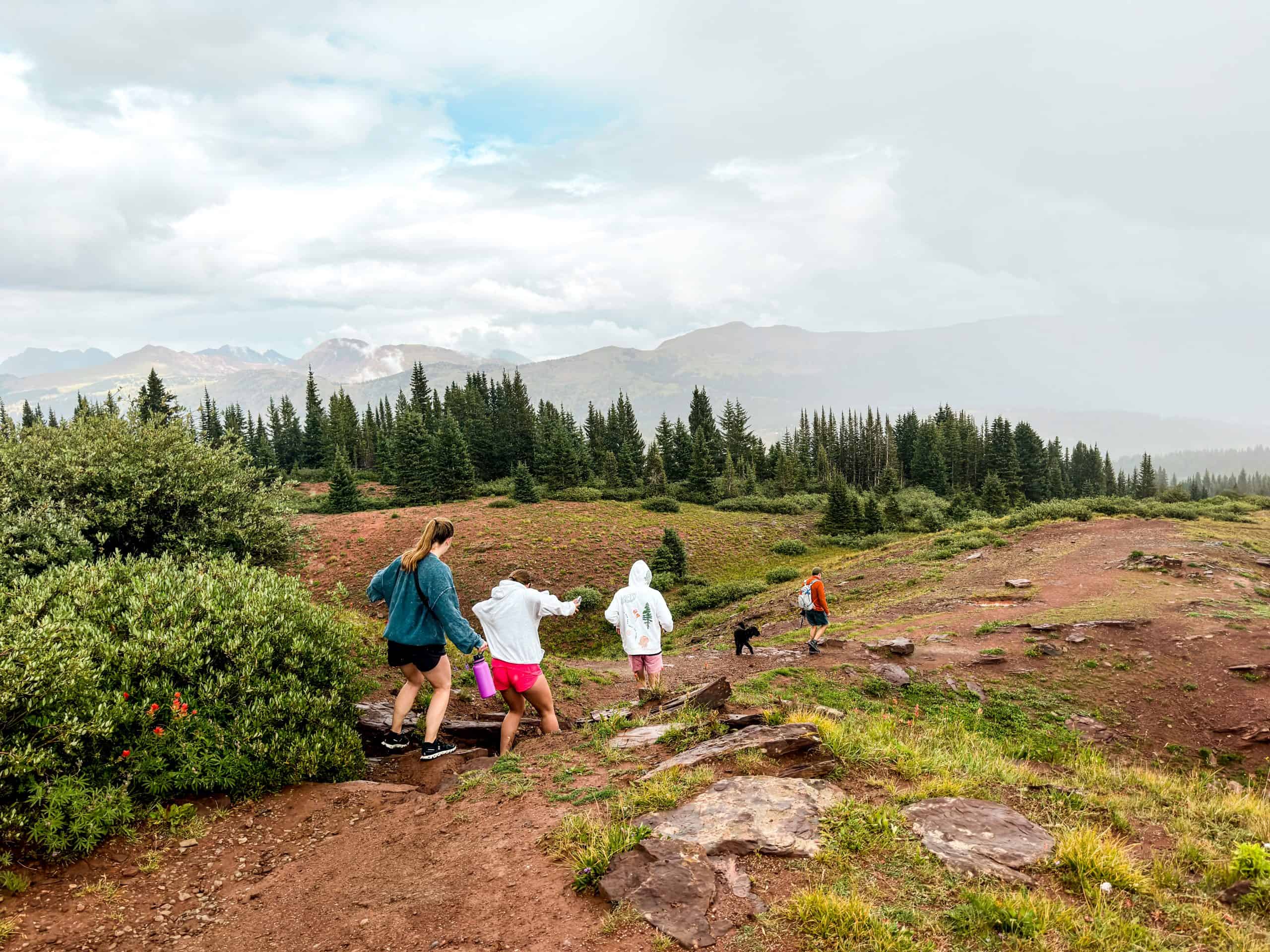 Group of friends hiking in the mountains near Vail, Colorado, with alpine scenery, rocky trails, and evergreen forests