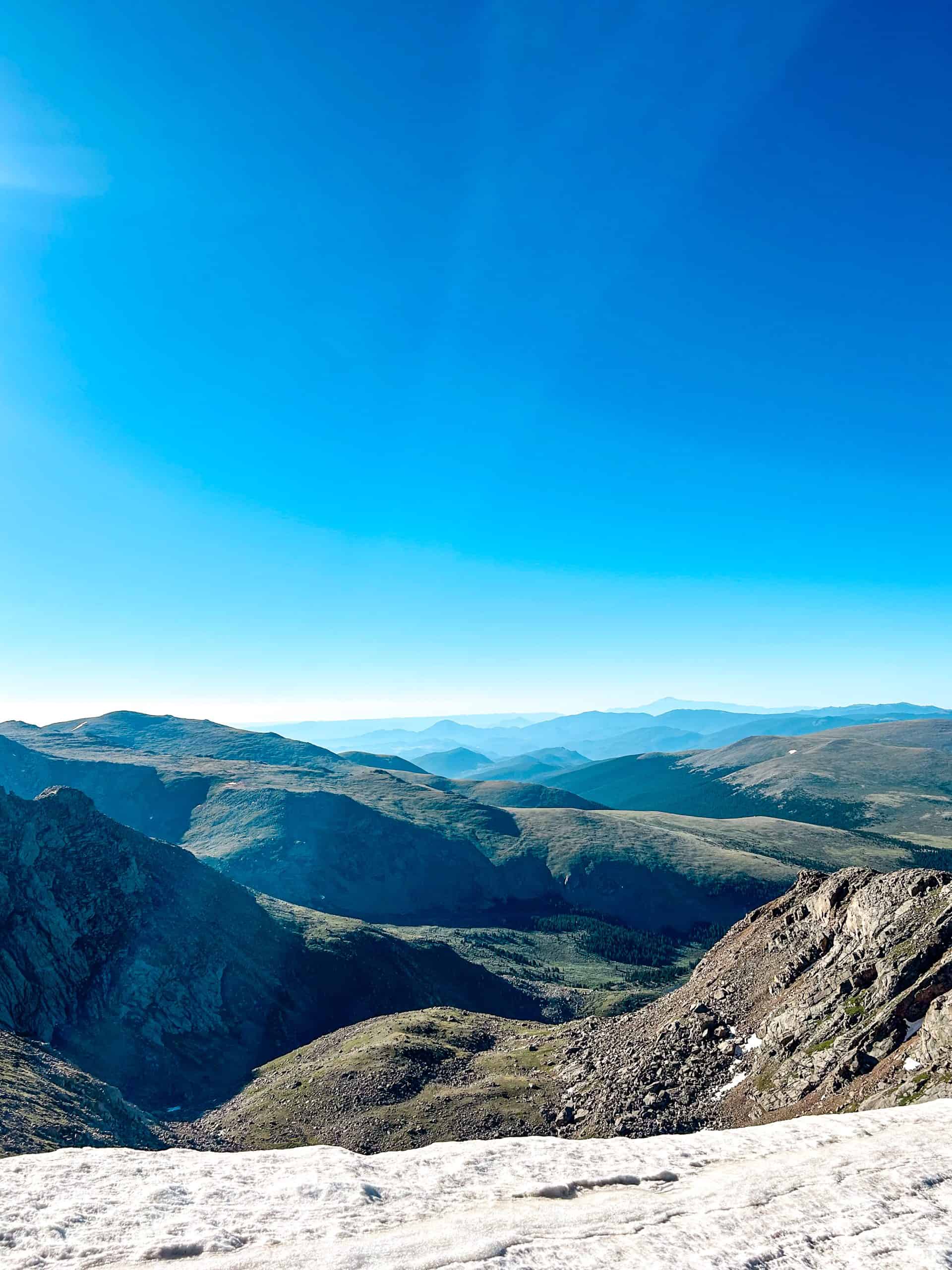 Panoramic view from Mount Bierstadt in Colorado, showing sweeping mountain ridges, alpine terrain, and a clear blue sky