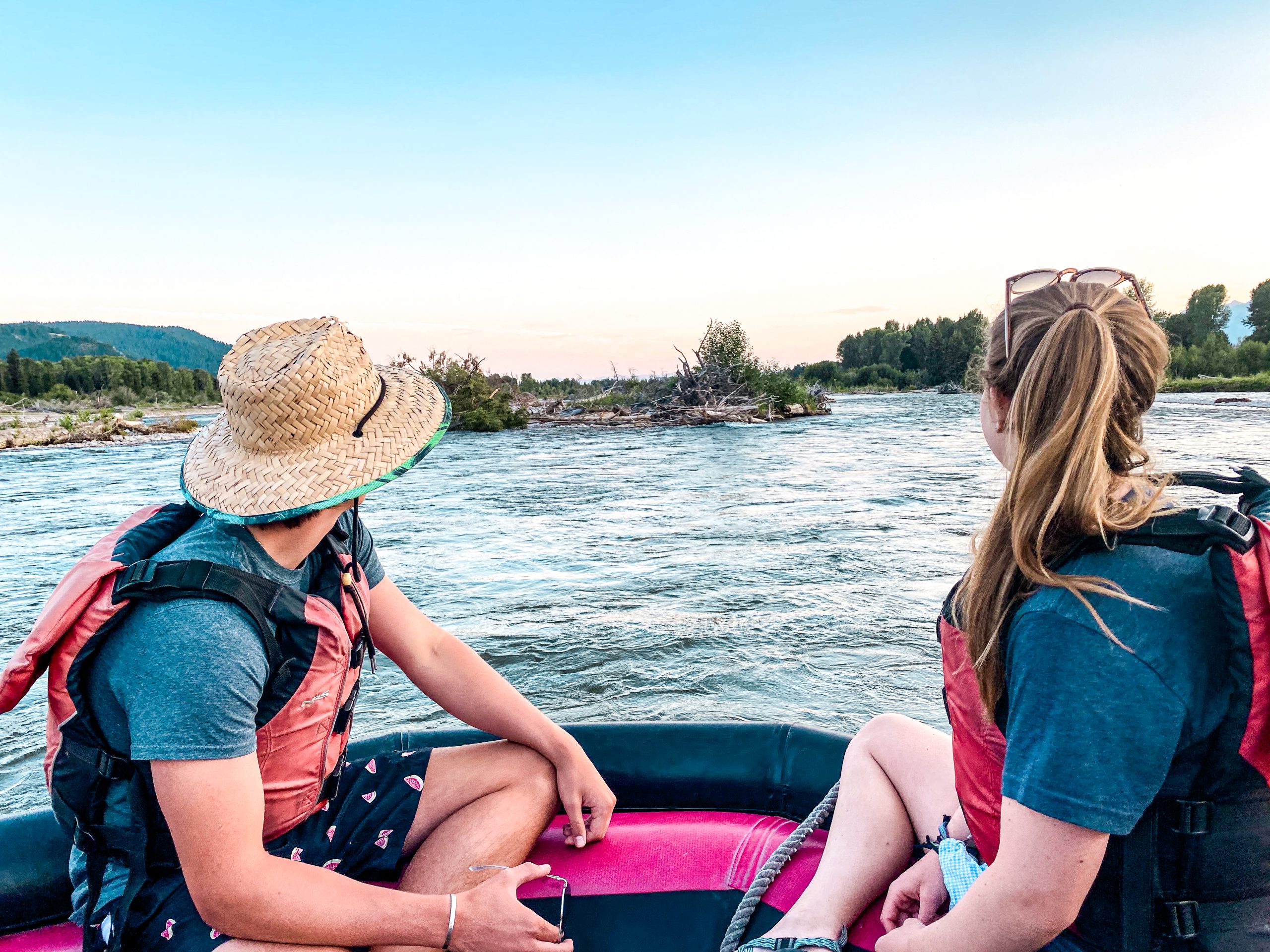 White water rafting in Colorado on a scenic river, with two people in a raft wearing life jackets and enjoying mountain views