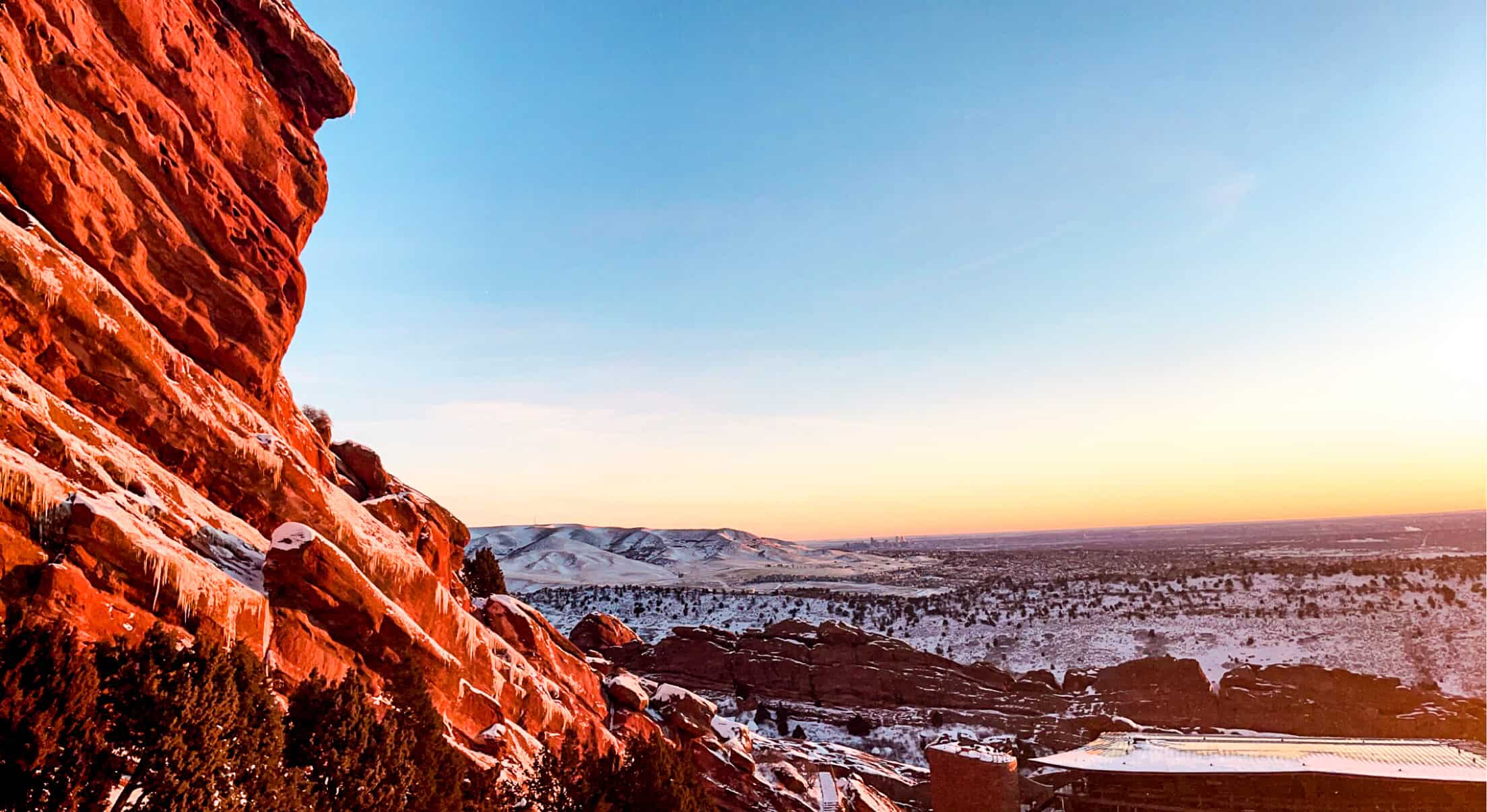 Red Rocks Amphitheatre at sunset near Morrison, Colorado, featuring red rock formations and city views