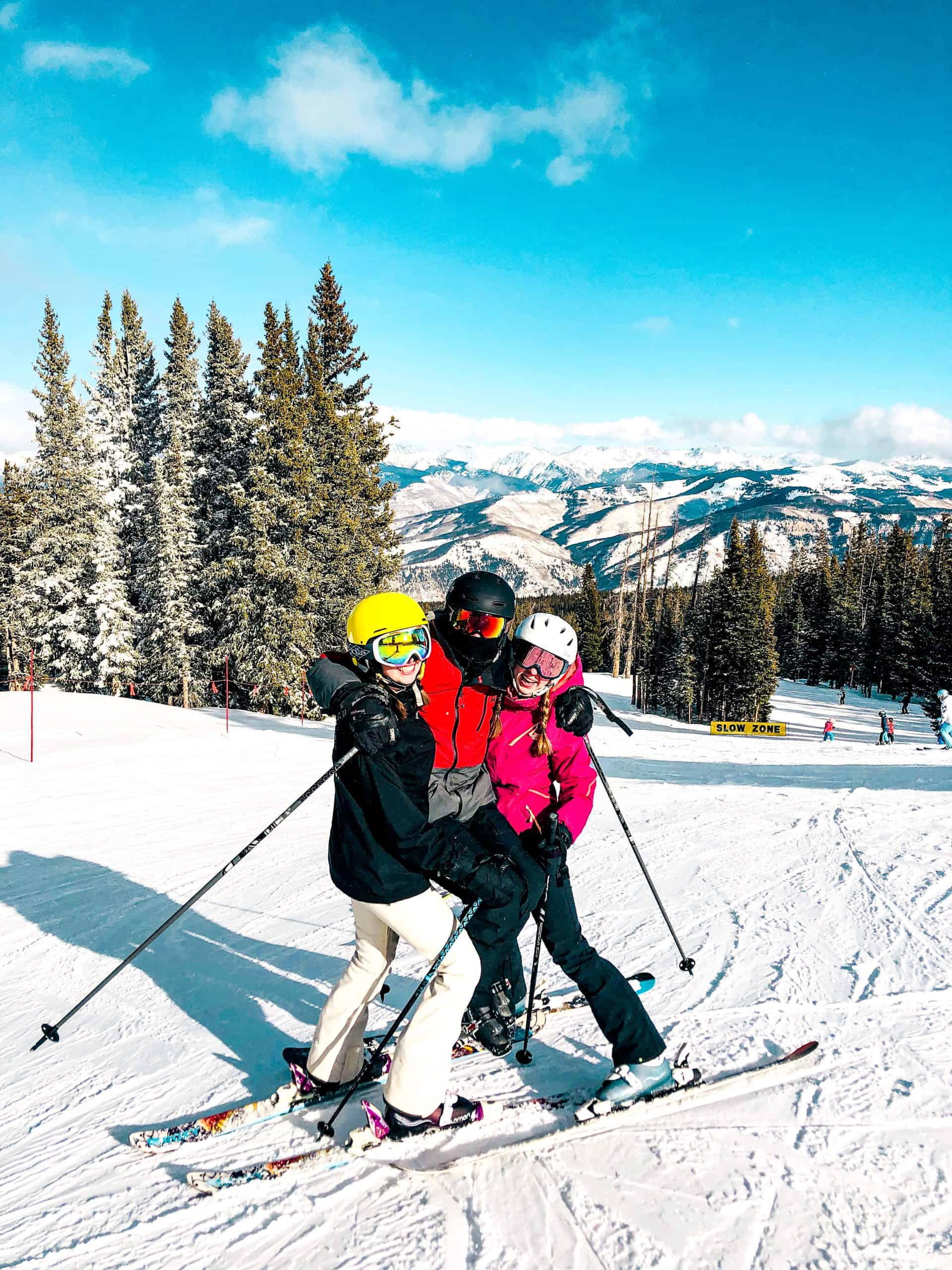 Group of friends skiing together at a Colorado ski resort with snowy trails, pine trees, and mountain views