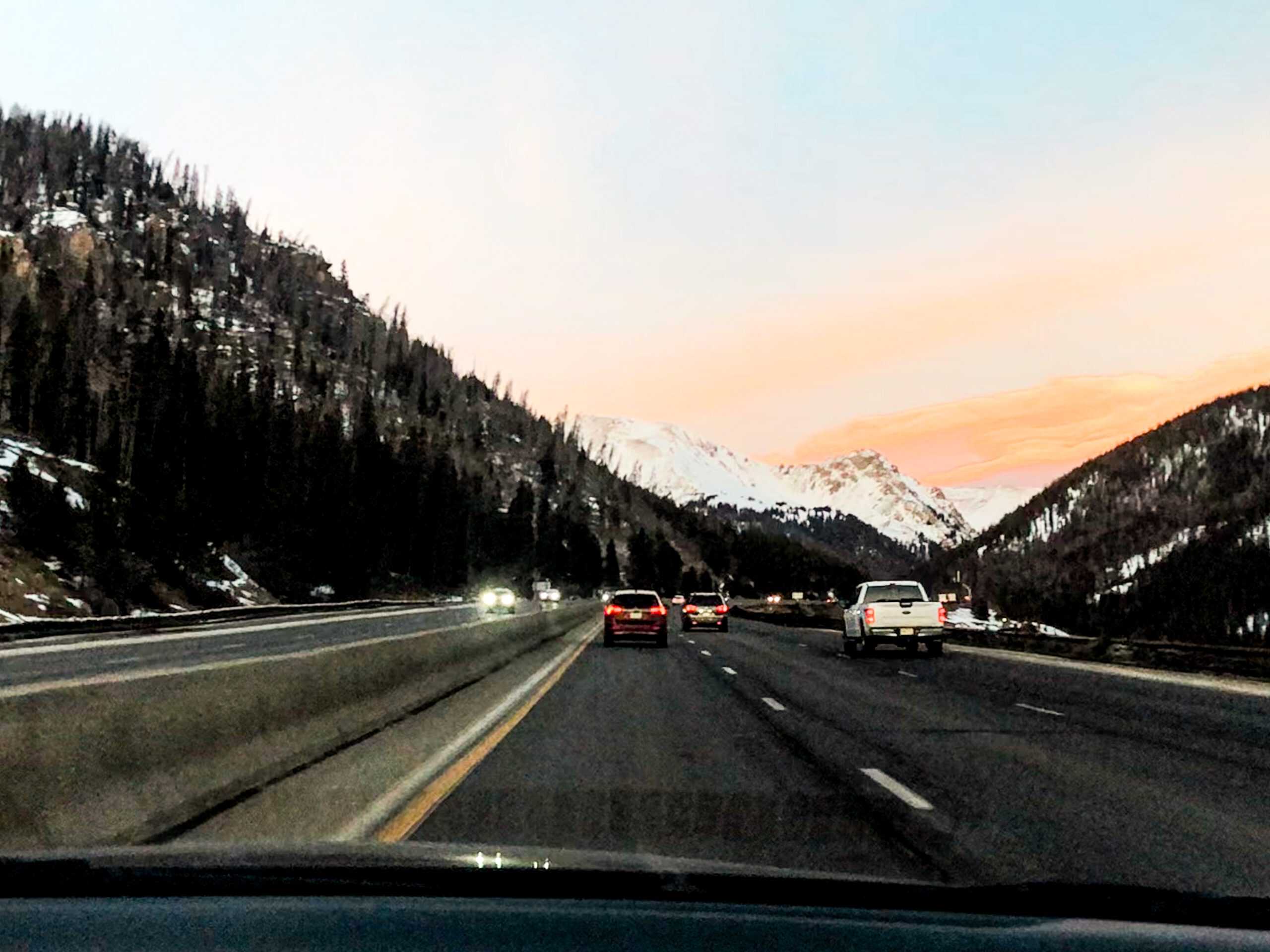 Driving on I-70 through the Colorado mountains at sunset on the way to popular day trips from Denver.