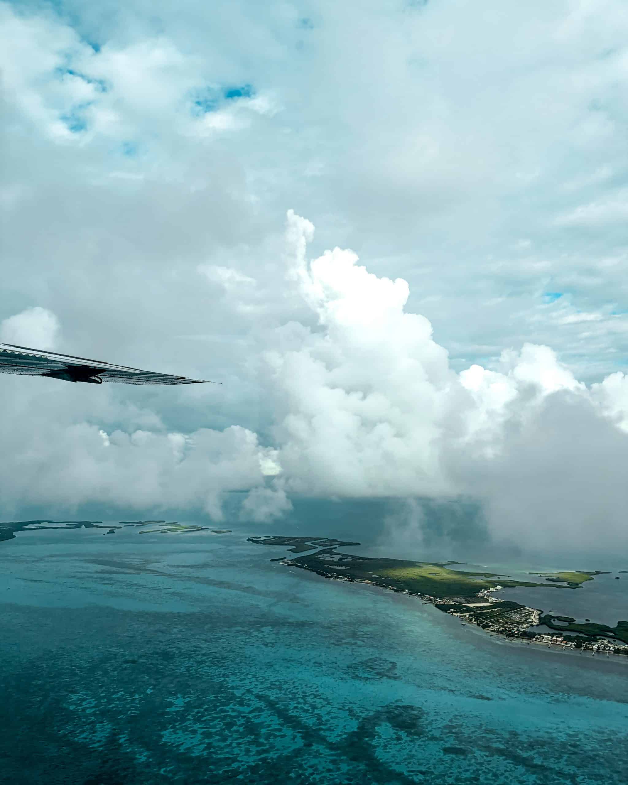 Turquoise ocean and a flat green island seen through a small local plane window in Belize