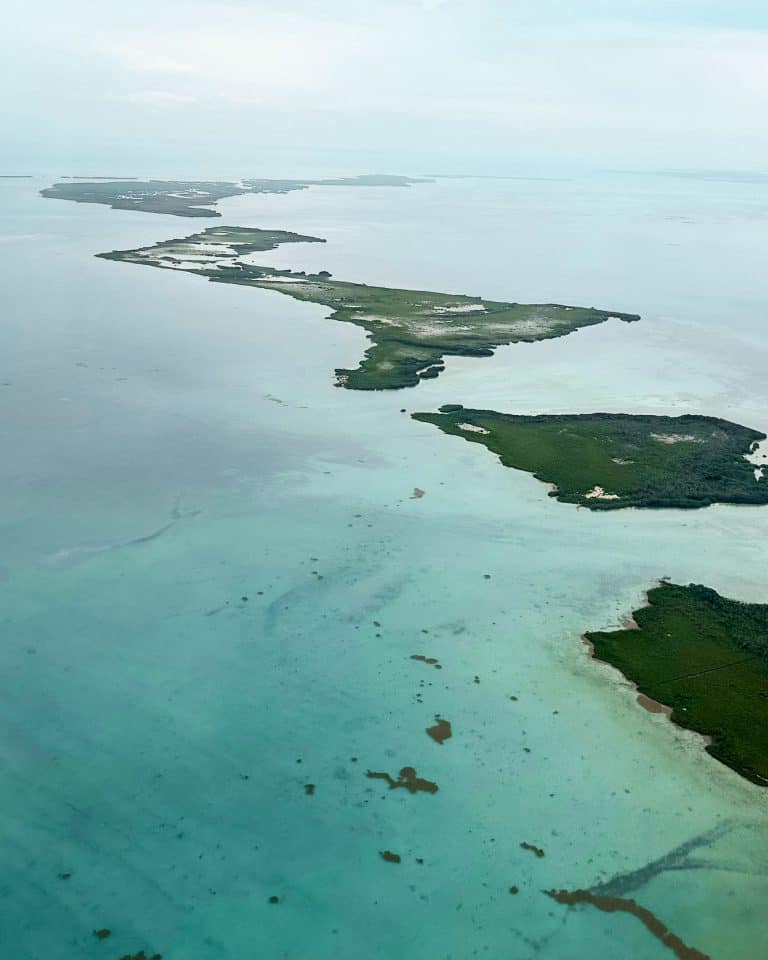Aerial view of small green islands scattered across turquoise water in Belize