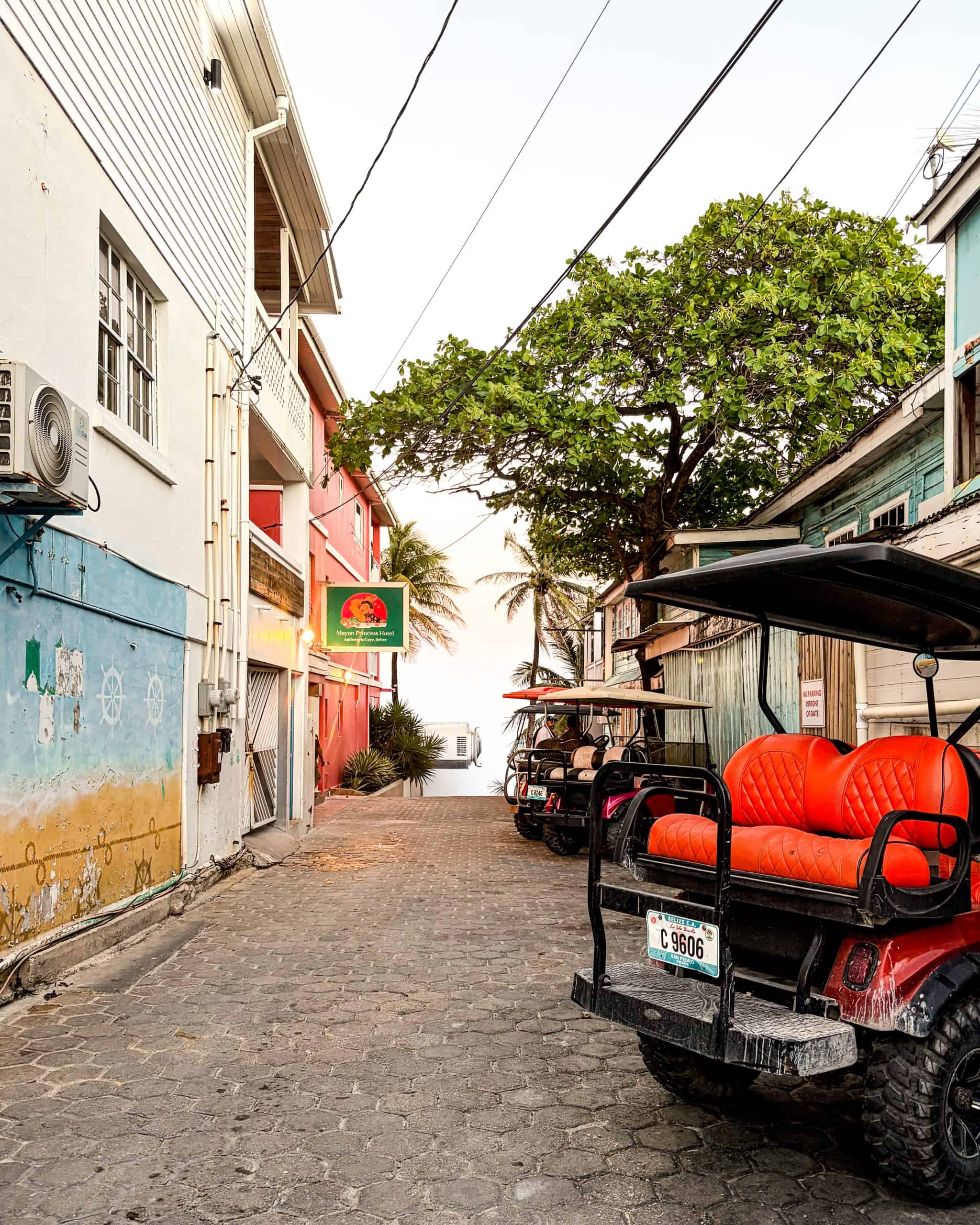 Cobblestone street lined with golf carts glowing under a sunset sky in San Pedro, Belize