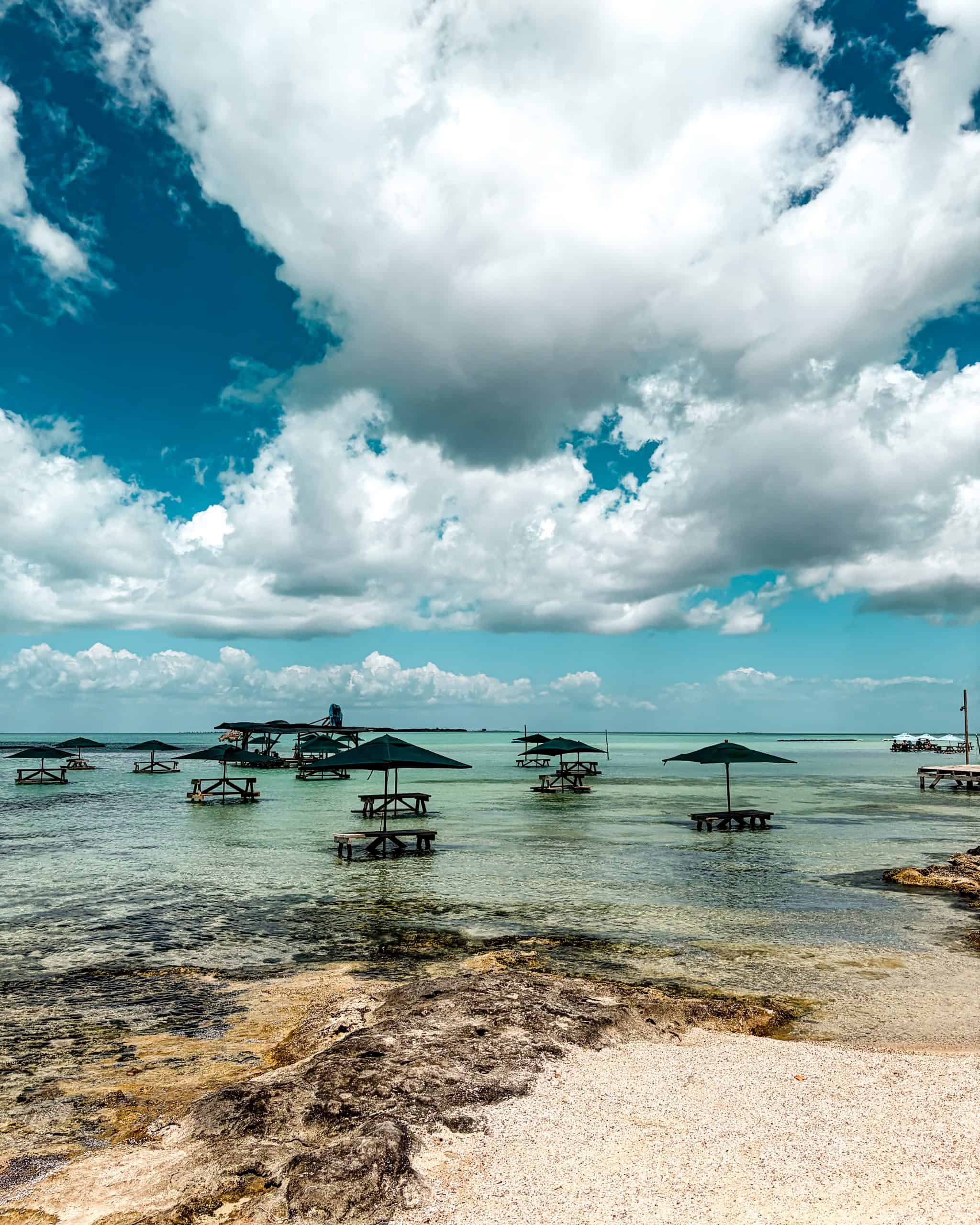 Wooden tables standing in clear blue water at sunset, San Pedro, Belize