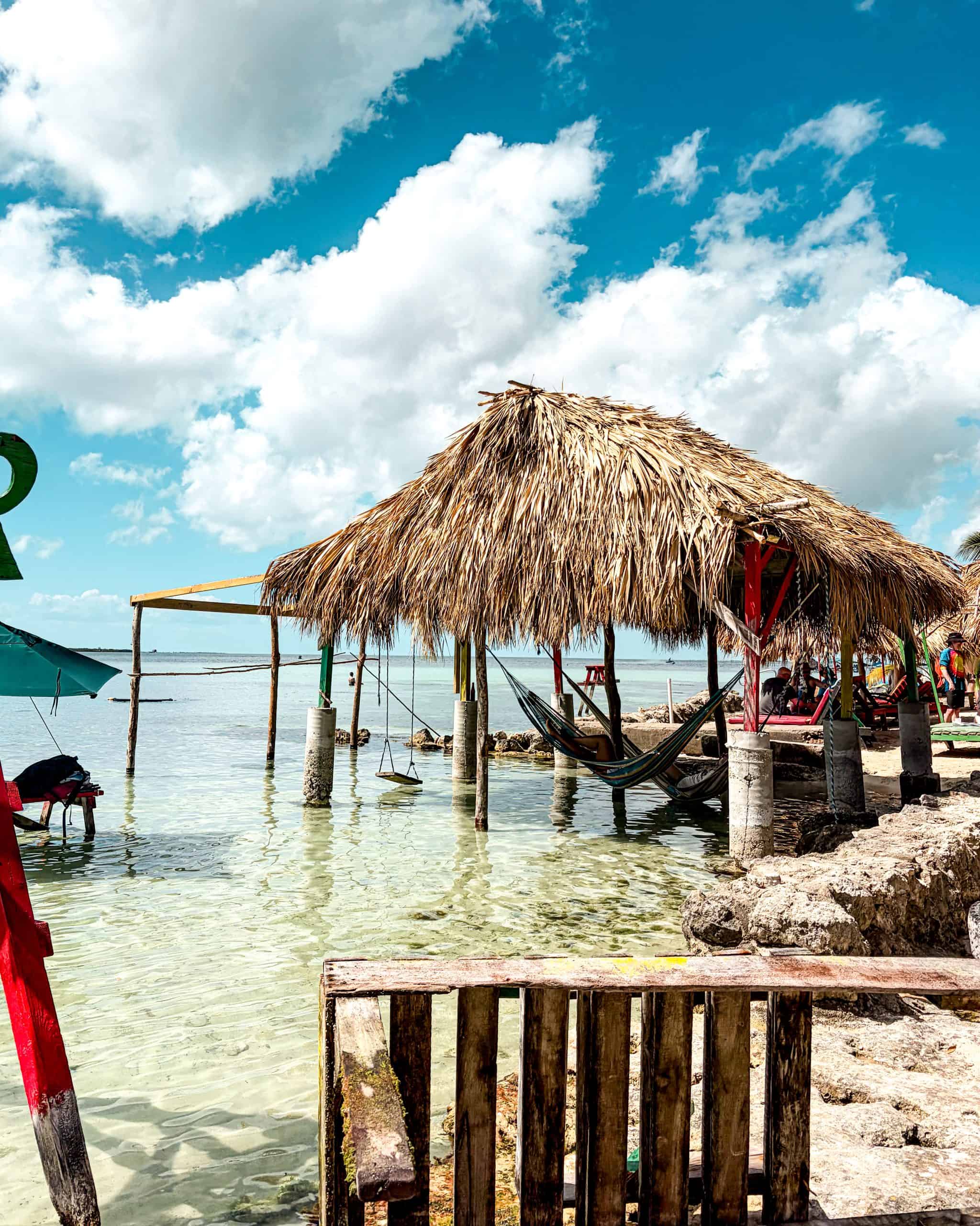 Hammocks suspended over calm turquoise water at Secret Beach, San Pedro, Belize