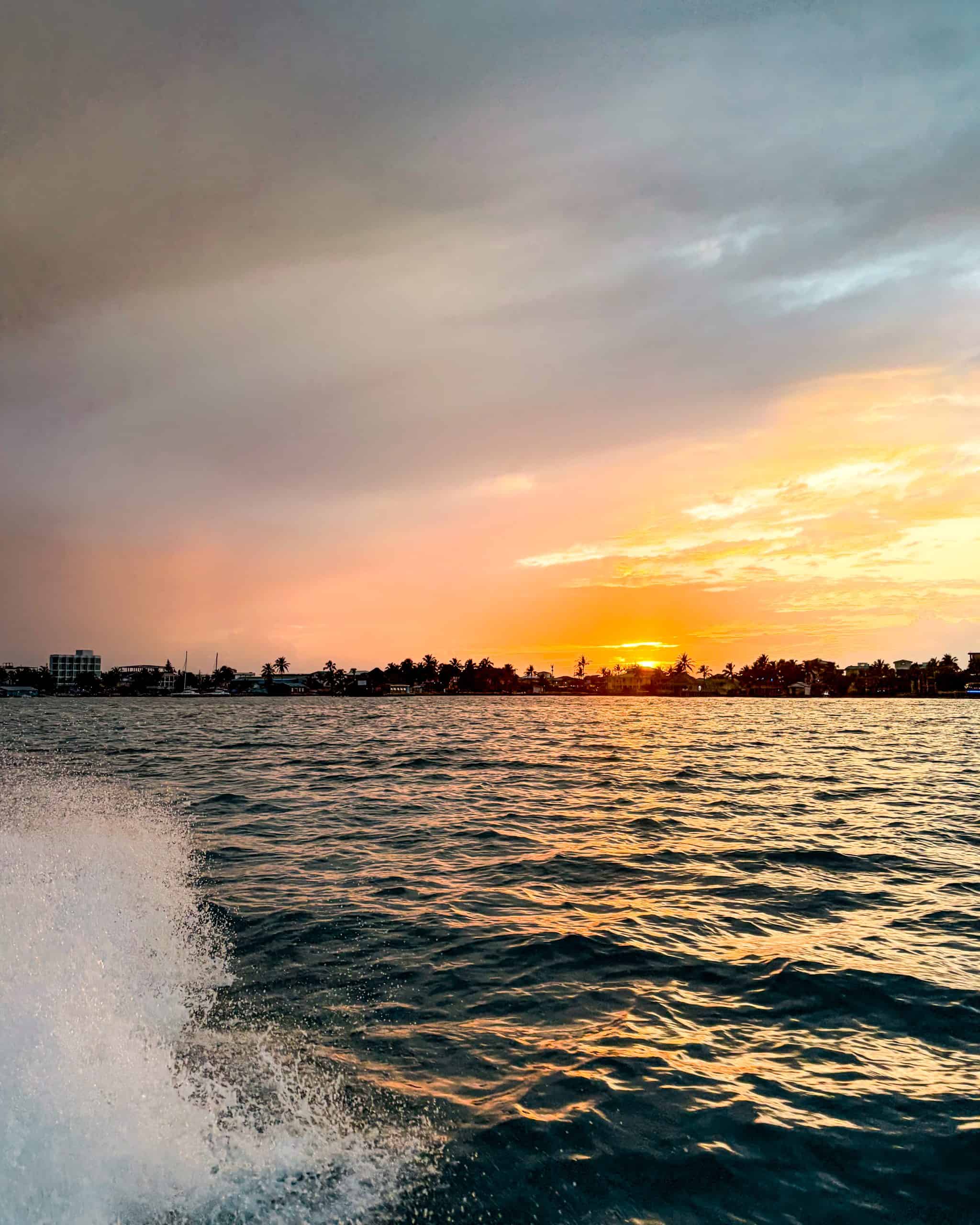 Warm orange sunset reflecting across calm water in San Pedro, Belize