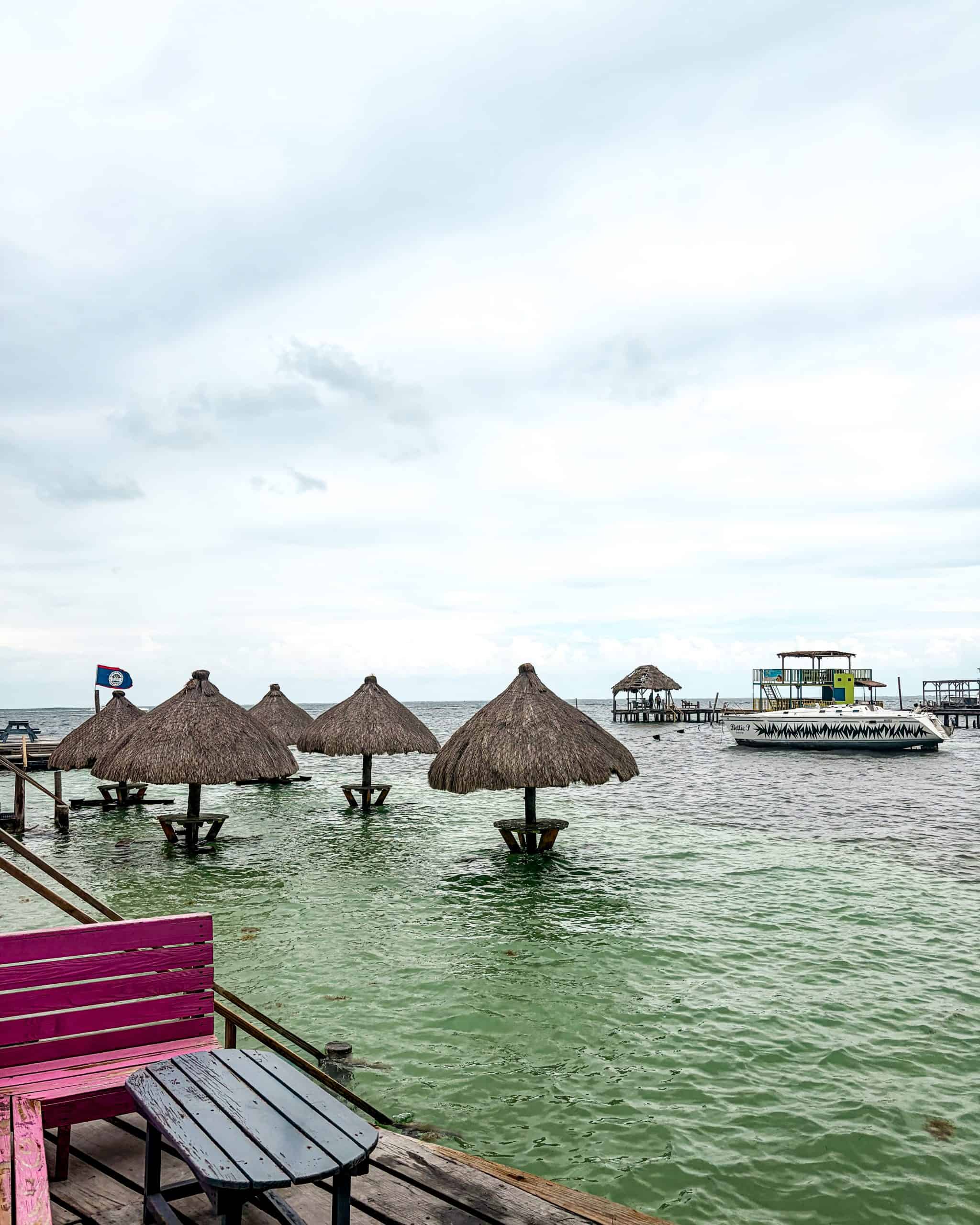 Wooden tables and bar stools set over shallow turquoise water at Caye Caulker, Belize